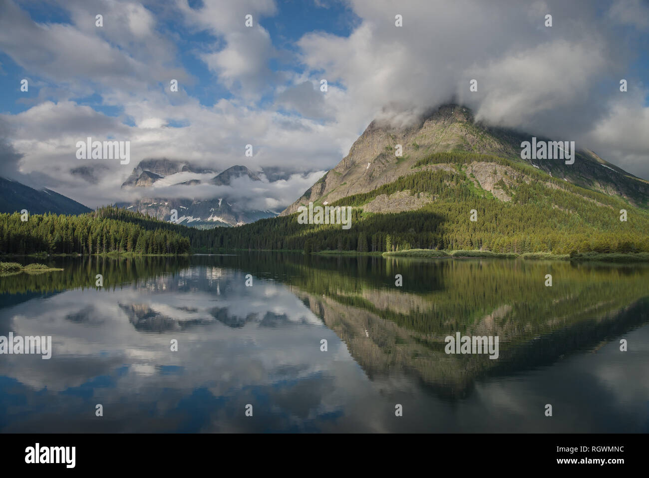 Ondeggianti bianche nuvole oscure le aspre picco del punto Grinnell, angolo ala, e l'altra aspre montagne che circondano il lago Swiftcurrent negli Stati Uniti " Foto Stock