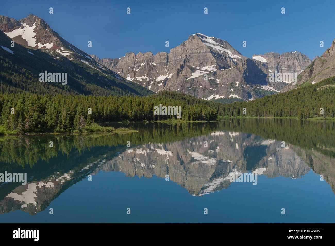 Le aspre pendici e il ghiacciaio di Angelo ala sono splendidamente riflesso in Swiftcurrent del lago in un giorno di estate nel parco nazionale di Glacier nel Montana Foto Stock
