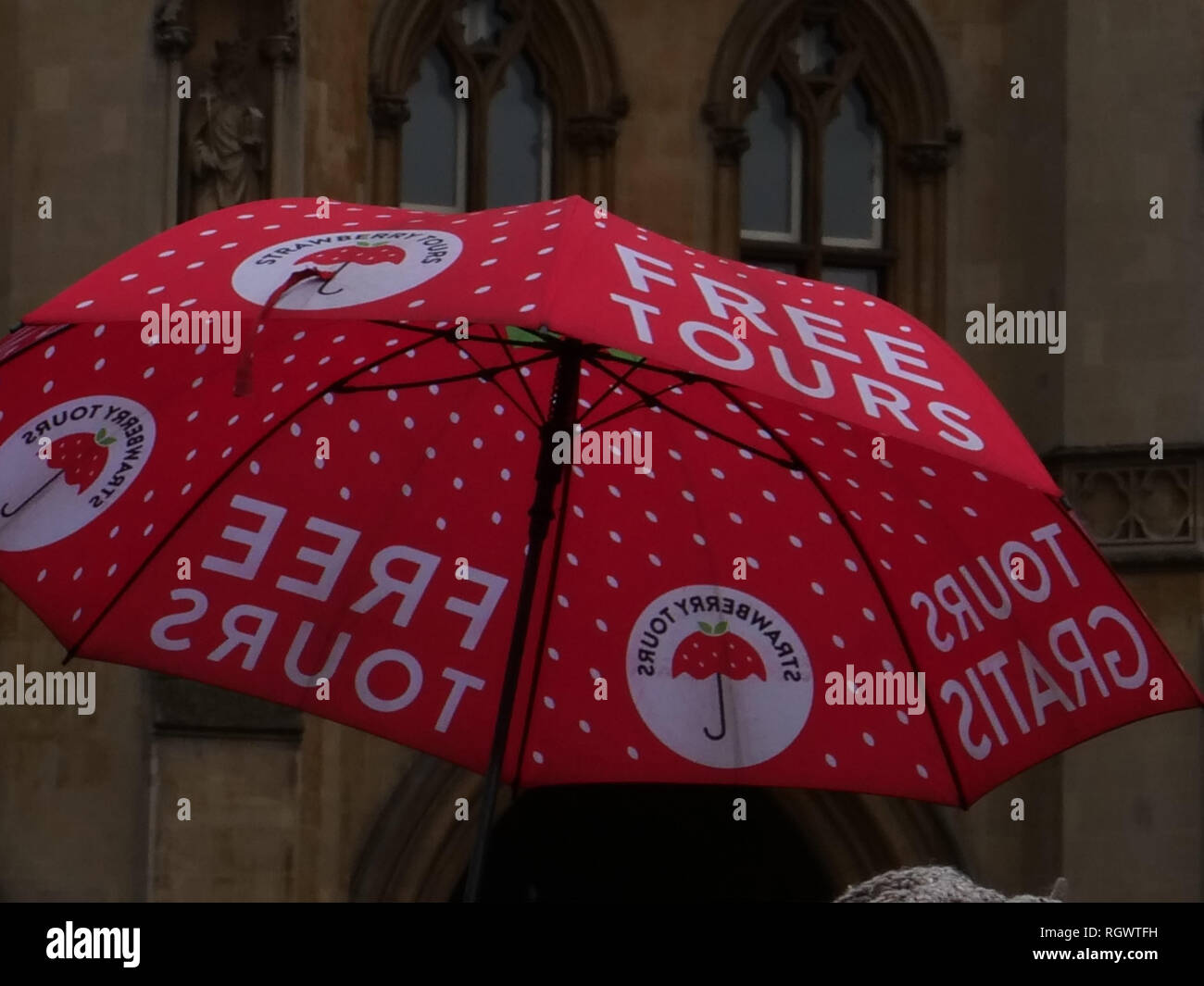 Ombrellone rosso raccogliendo i turisti per un tour a piedi di Londra, da un freelance e sapiente guida tour, alla scoperta dei luoghi più belli della capitale. Foto Stock