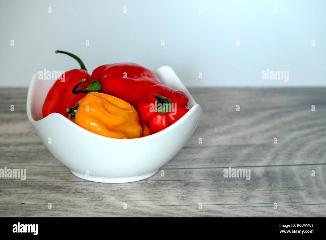 Peperoncino Habanero in una ciotola bianco su una lastra di legno. Foto Stock