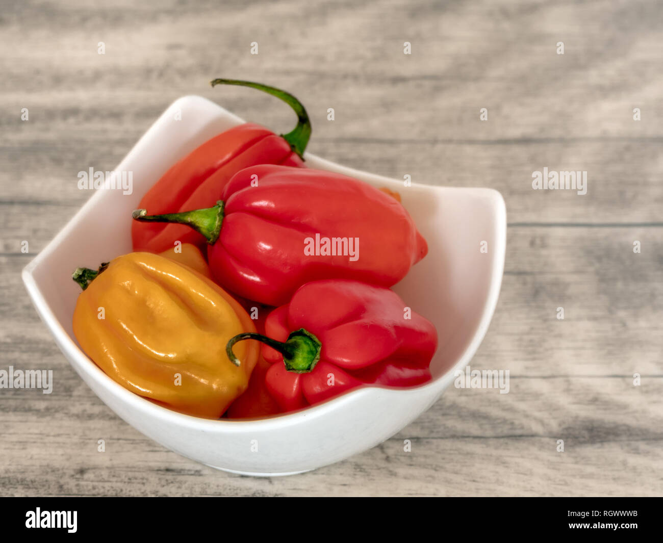 Peperoncino Habanero in una ciotola bianco su un tavolo di legno. Foto Stock