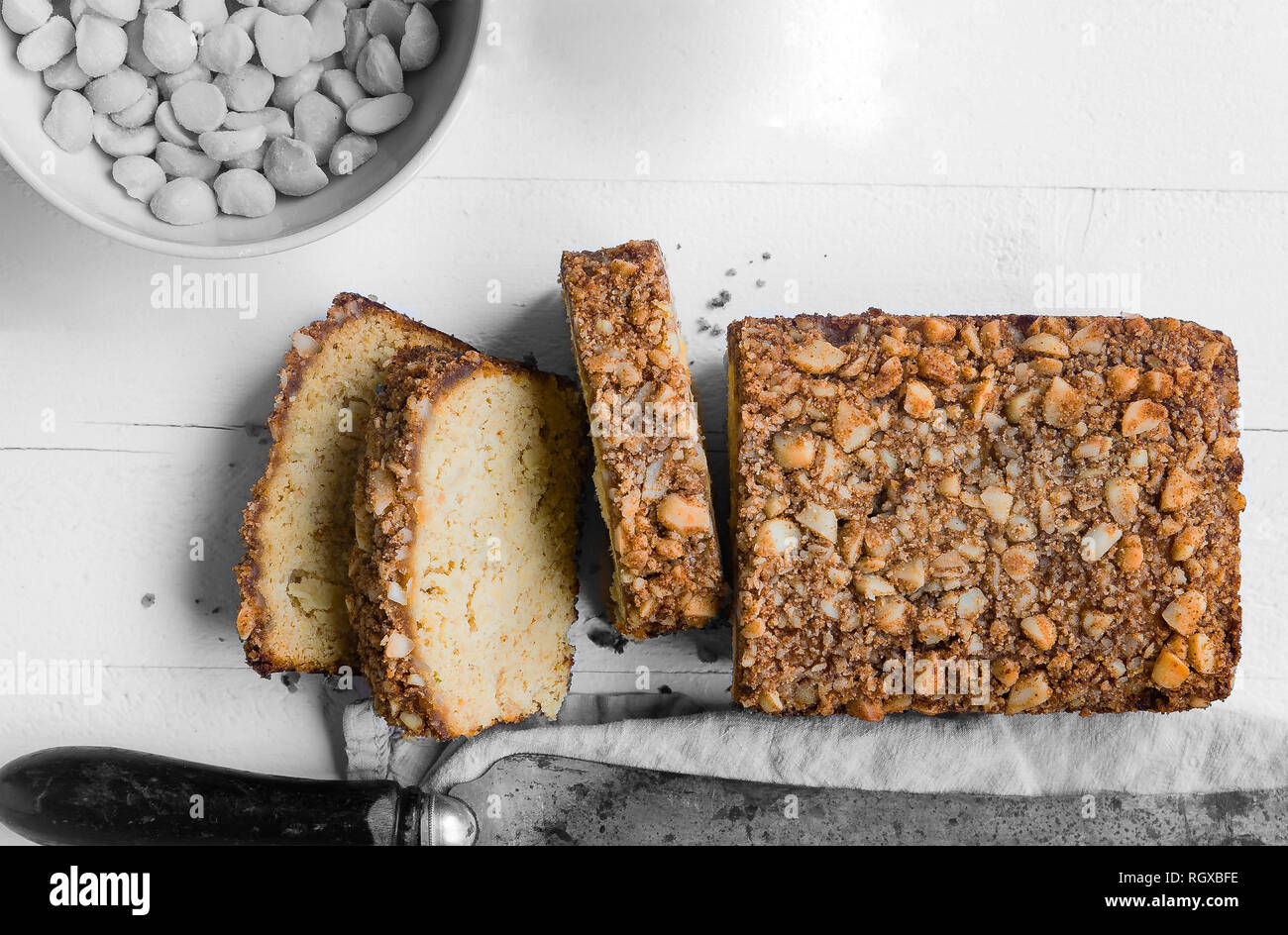 Una pagnotta di pane la posa su un tavolo con un coltello accanto ad essa e una ciotola di dadi, in bianco e nero, monocromatiche. Foto Stock