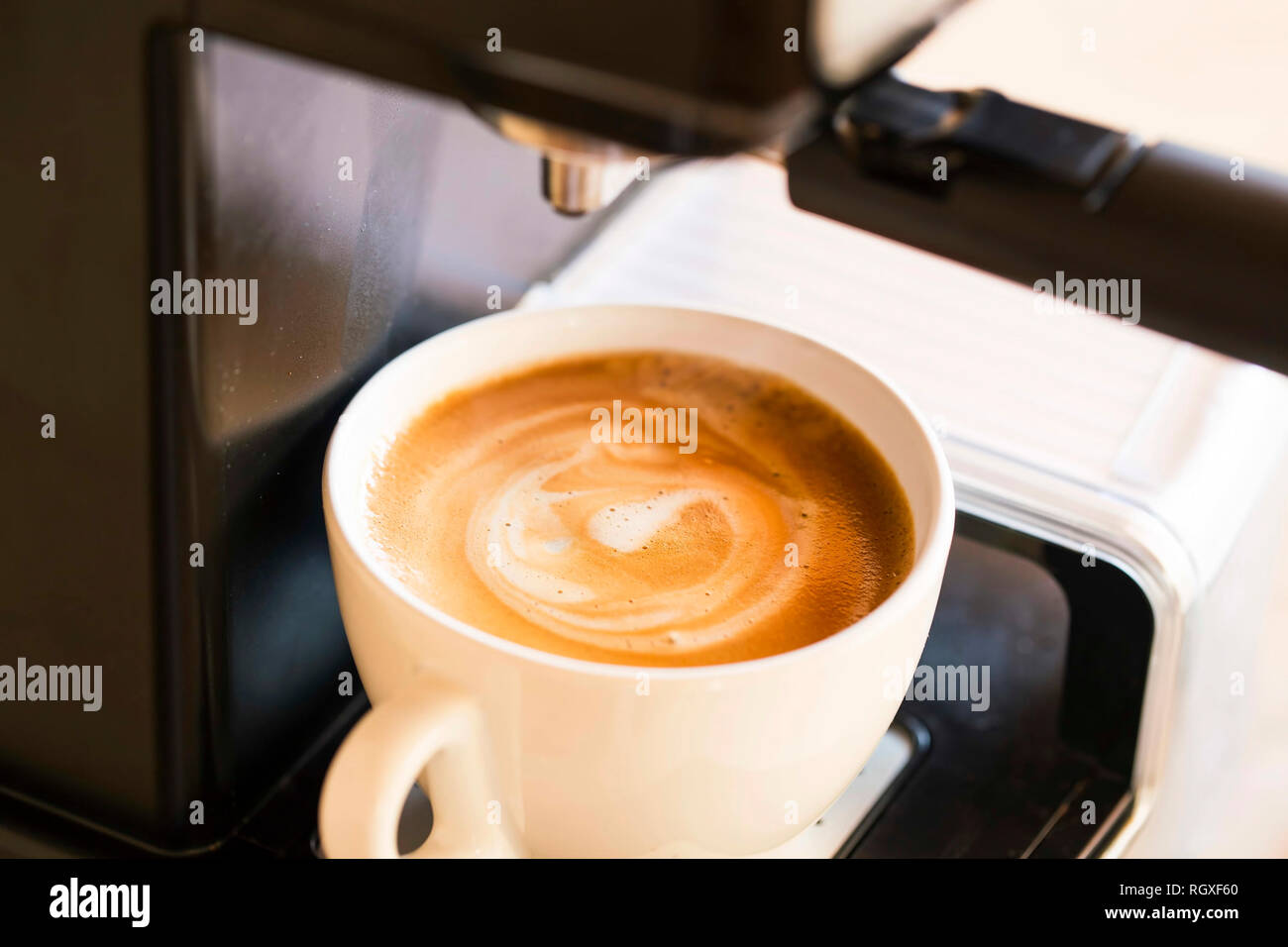 Tazza di cappuccino con crema soffice schiuma di latte, vista dall'alto sulla macchina per caffè , caffè appena fatto Foto Stock