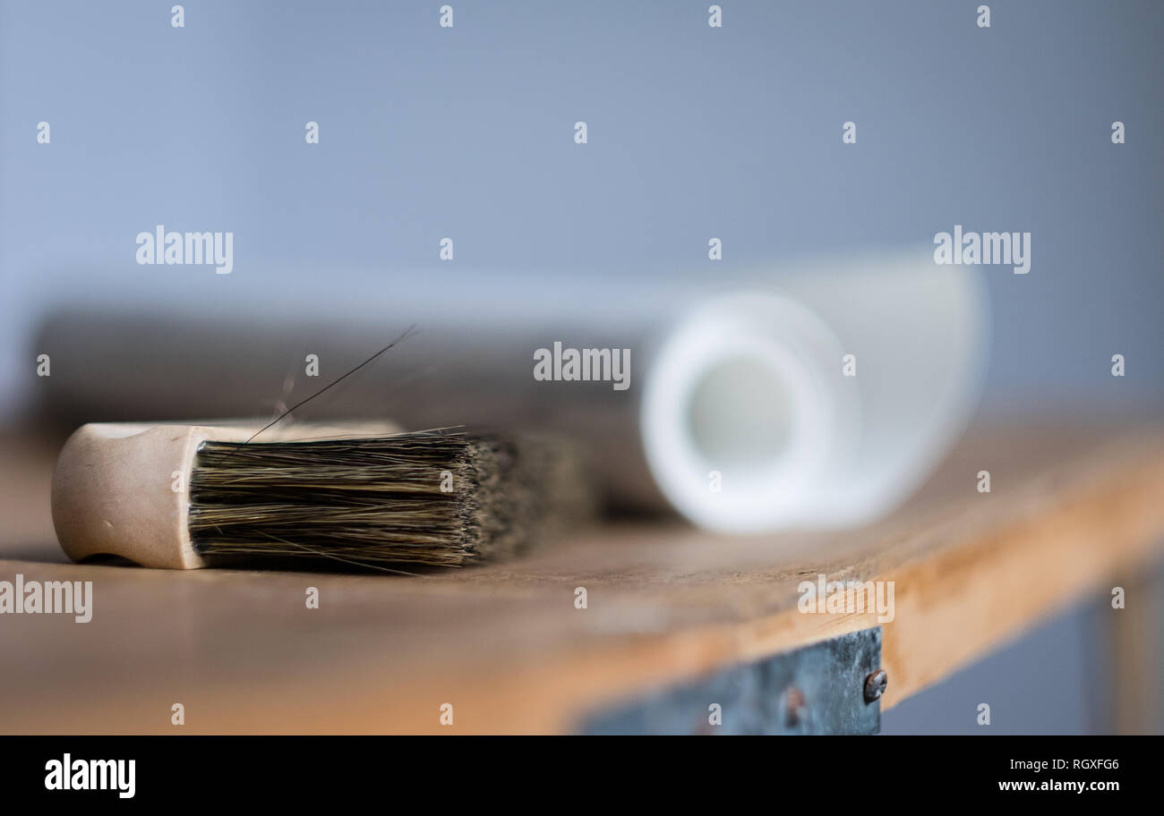 Spazzola di sfondo e un rotolo di carta da parati su una tabella di incollaggio pronto per decorare una stanza Foto Stock