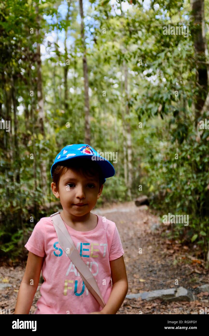 Un ritratto di una giovane ragazza carina in piedi su un percorso in una foresta, Finch Hatton, Queensland 4756, Australia Foto Stock