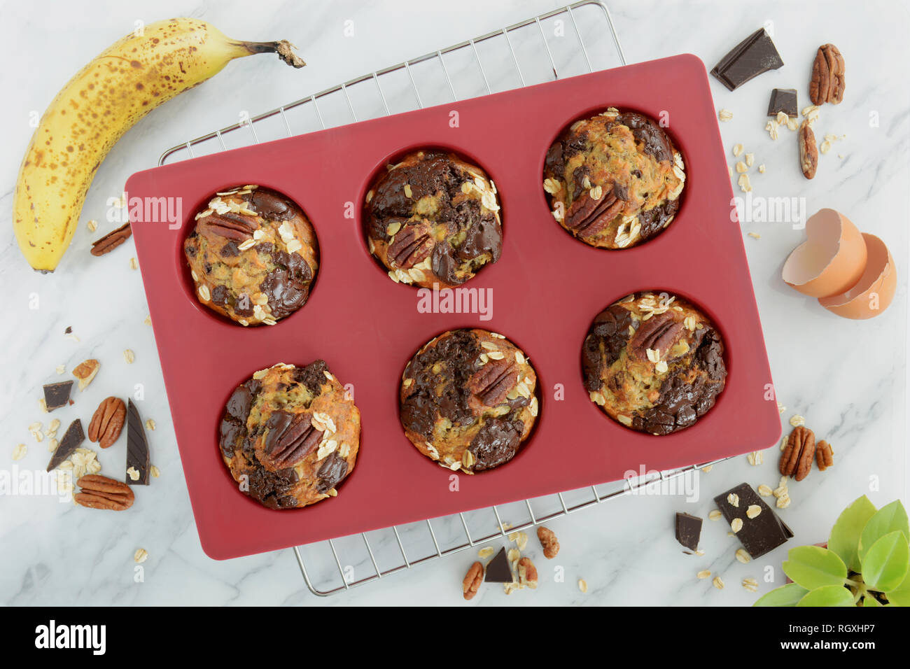 Freschi di forno di fiocchi d'avena e banana pecan e muffin al cioccolato in silicone rosso teglia per muffin shot da sovraccarico nella luce naturale. Una sana e nutriente merenda. Foto Stock