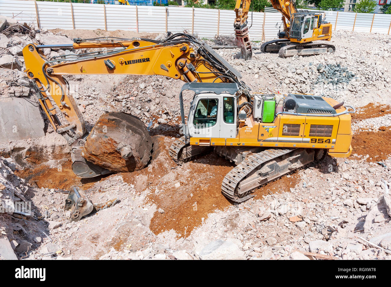 Decostruzione sito. Un Liebherr 954 escavatore, con una benna , estrae un grande blocco di cemento residue dalle fondamenta di un edificio. Foto Stock