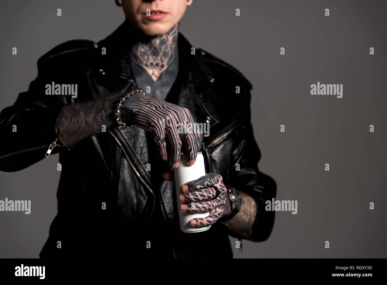 Ritagliato colpo di tatuati uomo in giacca di pelle soda di apertura può essere isolato su grigio Foto Stock
