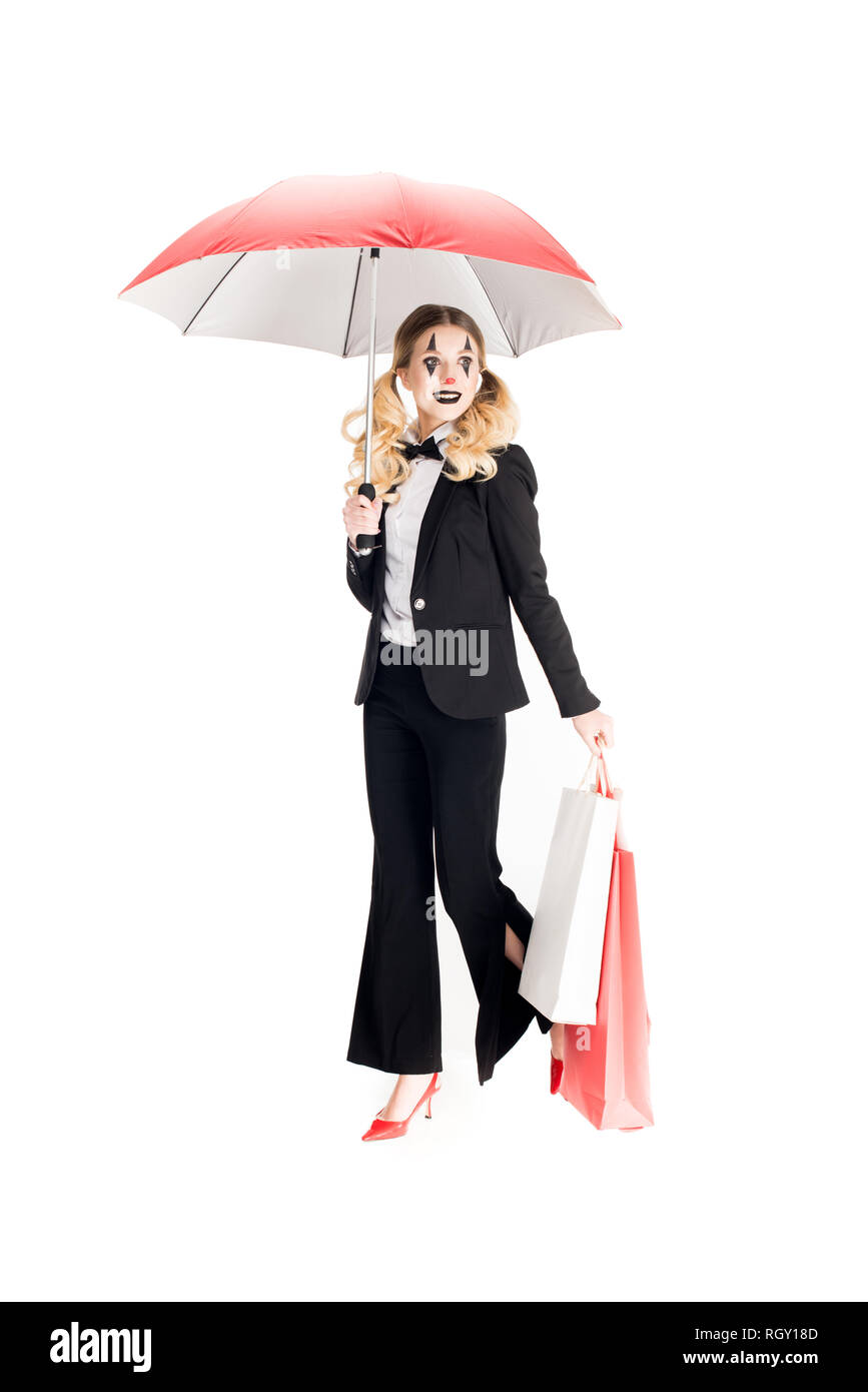 Donna sorridente clown holding shopping bags e ombrello isolato su bianco Foto Stock