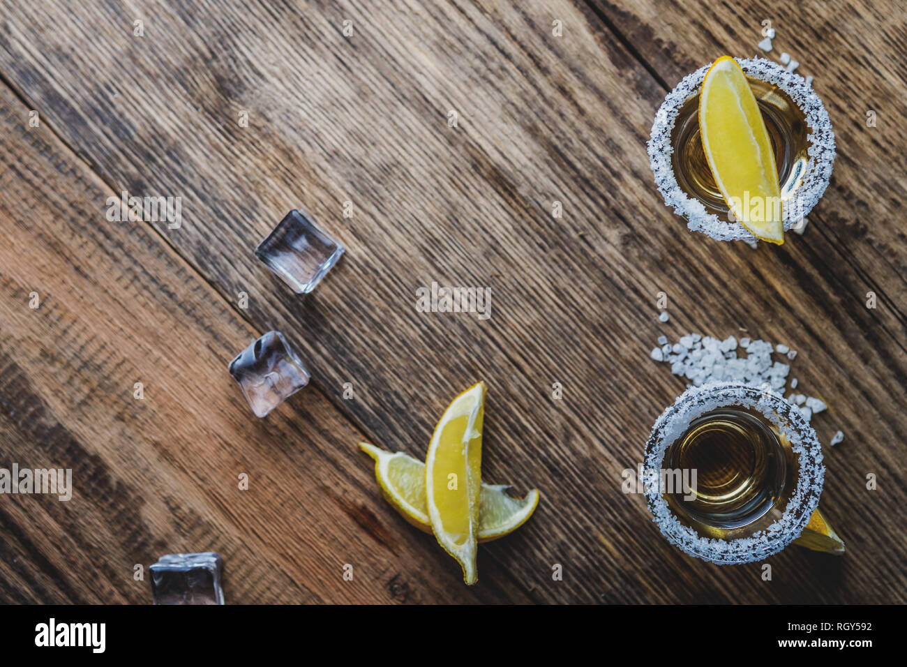 Tradizionale messicano alcool bere la tequila con limone e sale e cubo di ghiaccio sul tavolo di legno vista superiore Foto Stock