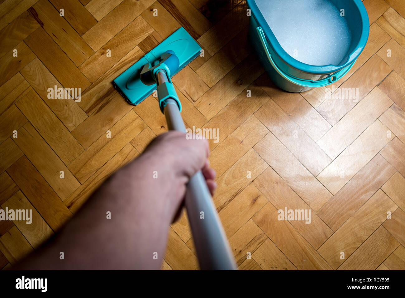 Tergi sporco pavimento in legno da bagnato tergivetro mop, i lavori di casa. L'uomo la pulizia della casa. Topview Foto Stock
