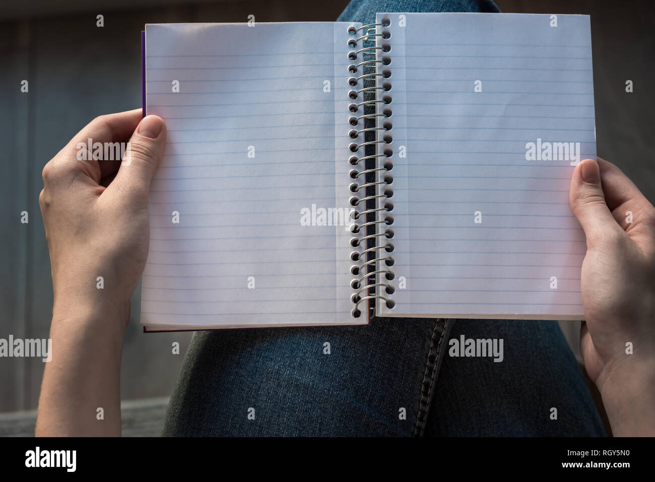 Donna di mani tenendo aperto il notebook foderati foderato con pagine su lap Foto Stock