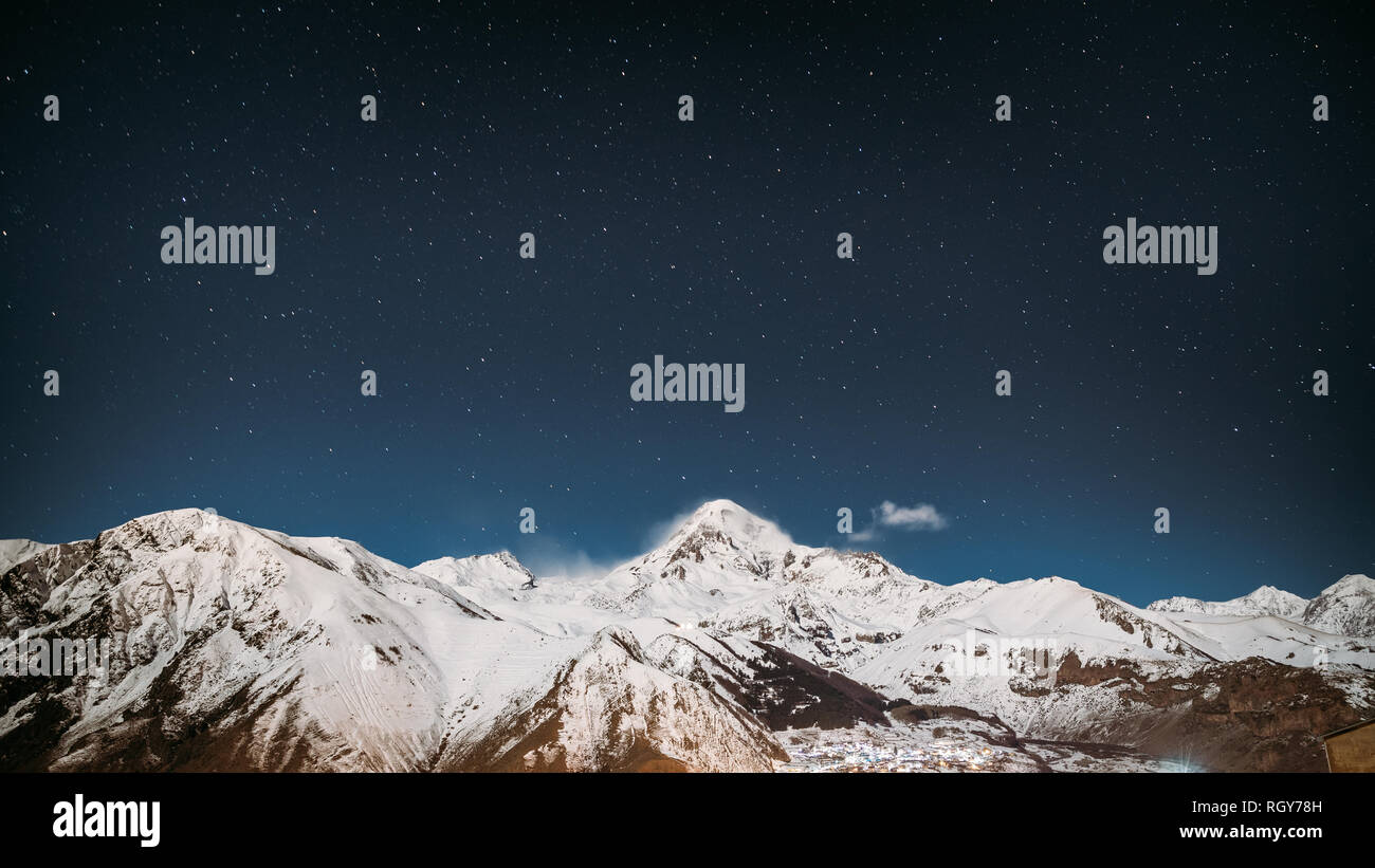 Stepantsminda, Georgia. Notte invernale cielo stellato con incandescente stelle sulla cima del monte Kazbek coperte di neve. Bella notte invernale georgiano Landsc Foto Stock