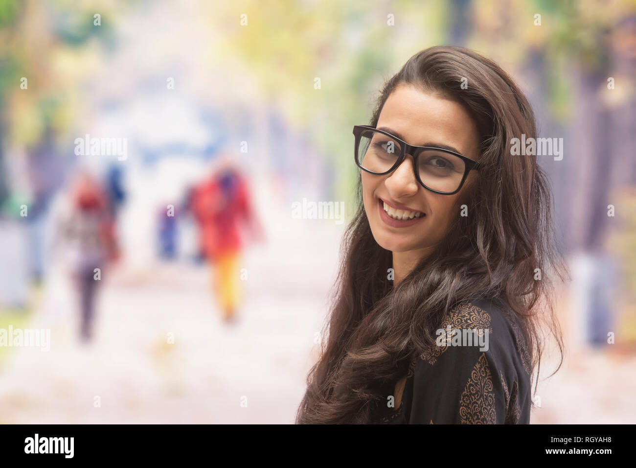 Ritratto di una giovane e bella donna sorridente guardando la telecamera indossando occhiali da vista sulla strada Foto Stock