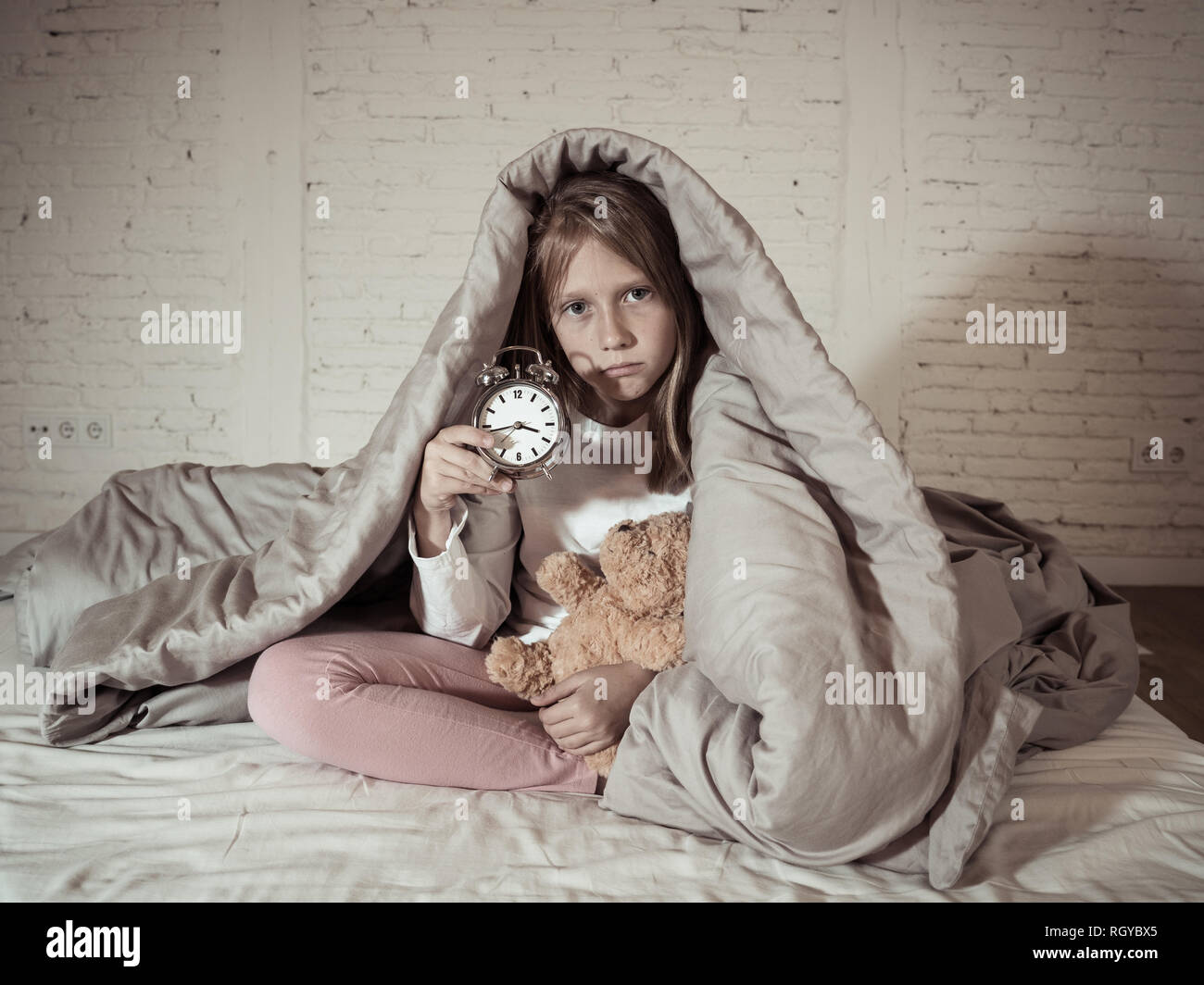 Carino piccolo insonni ragazza seduta sul letto guardando triste e stanco aventi disturbi del sonno soggiorno addormentato durante la notte o alla riattivazione troppo presto al mattino in Foto Stock