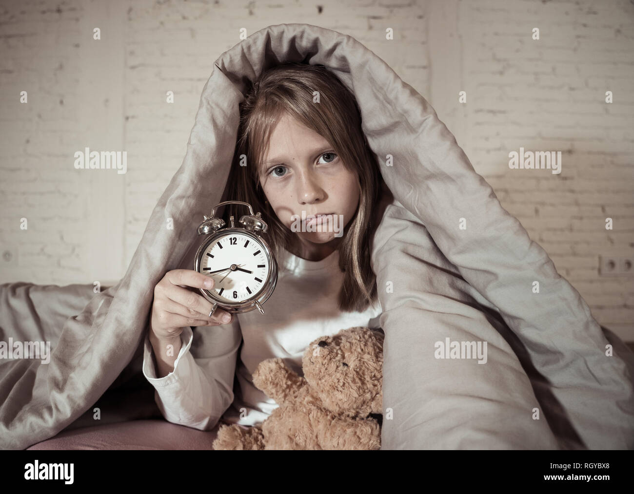 Carino piccolo insonni ragazza seduta sul letto guardando triste e stanco aventi disturbi del sonno soggiorno addormentato durante la notte o alla riattivazione troppo presto al mattino in Foto Stock