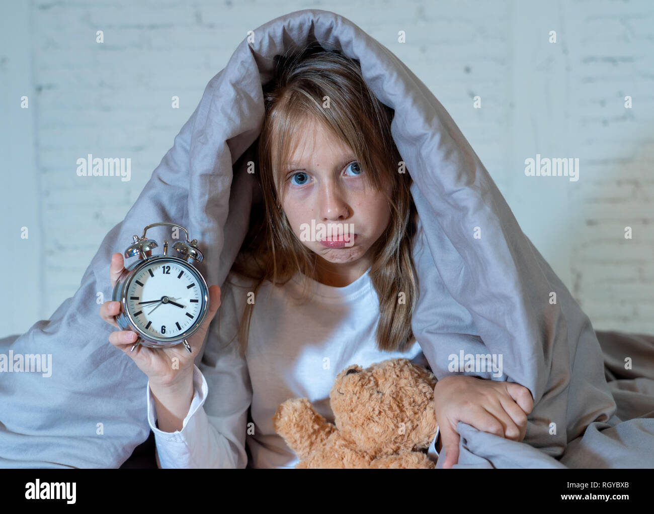 Carino piccolo insonni ragazza seduta sul letto guardando triste e stanco aventi disturbi del sonno soggiorno addormentato durante la notte o alla riattivazione troppo presto al mattino in Foto Stock