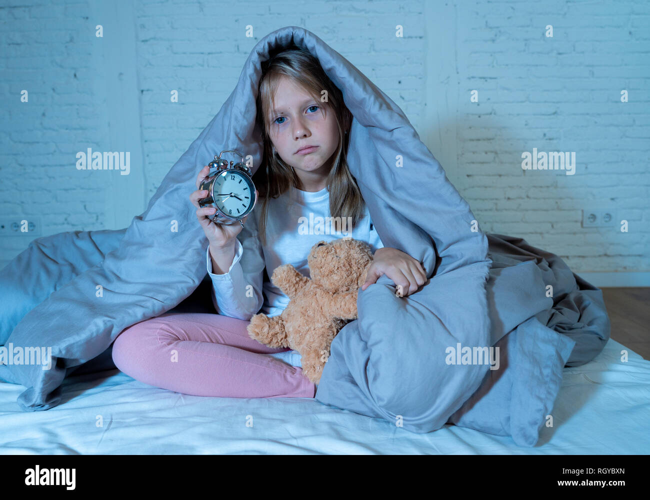 Carino piccolo insonni ragazza seduta sul letto guardando triste e stanco aventi disturbi del sonno soggiorno addormentato durante la notte o alla riattivazione troppo presto al mattino in Foto Stock