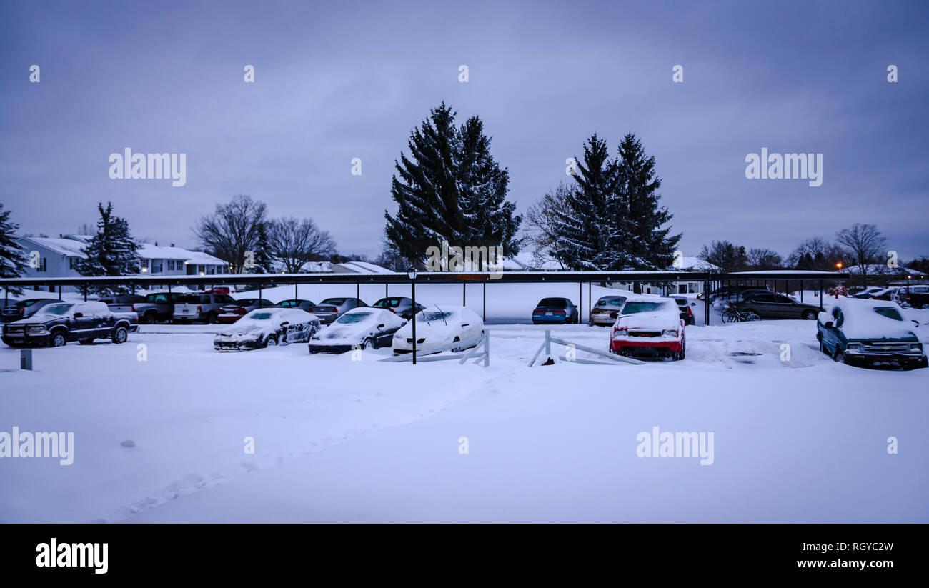 Una sera d'inverno. Un blocco di appartamenti auto, e il parcheggio coperto da una spessa coltre di neve. I primi di febbraio tempesta di neve nel Michigan, Stati Uniti d'America. Foto Stock