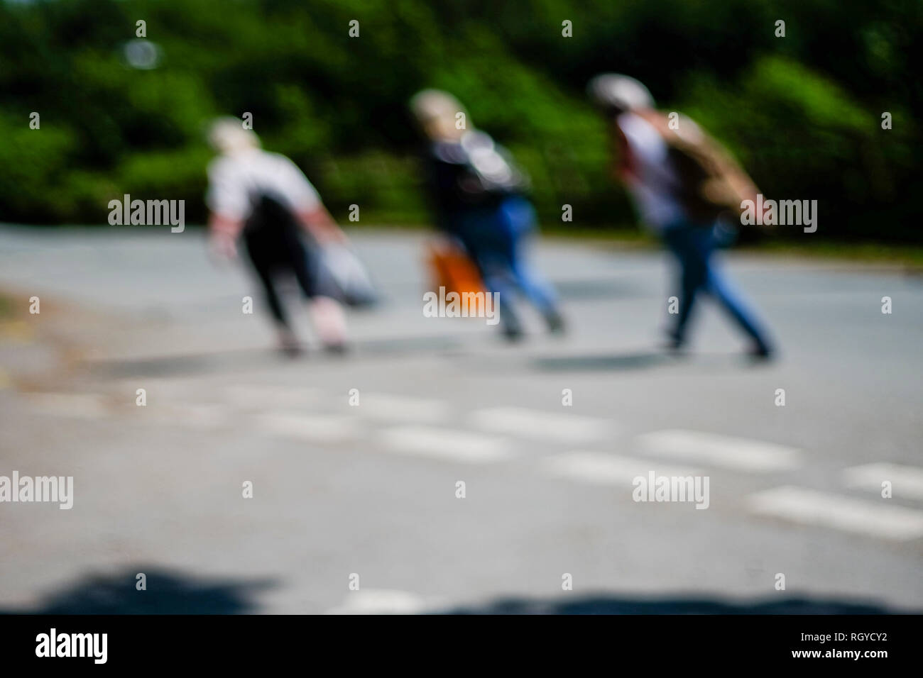 Tre persone a piedi lungo una strada che porta i sacchetti e sfocata di astrazione. Foto Stock