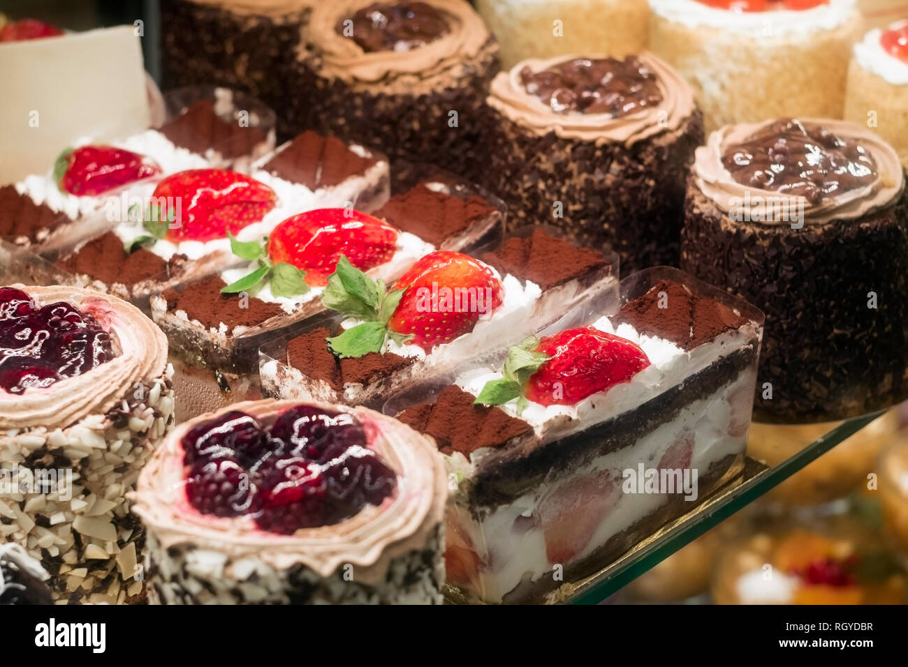 Fragola deliziosa, blackberry e torte al cioccolato in una pasticceria nella finestra di visualizzazione Foto Stock