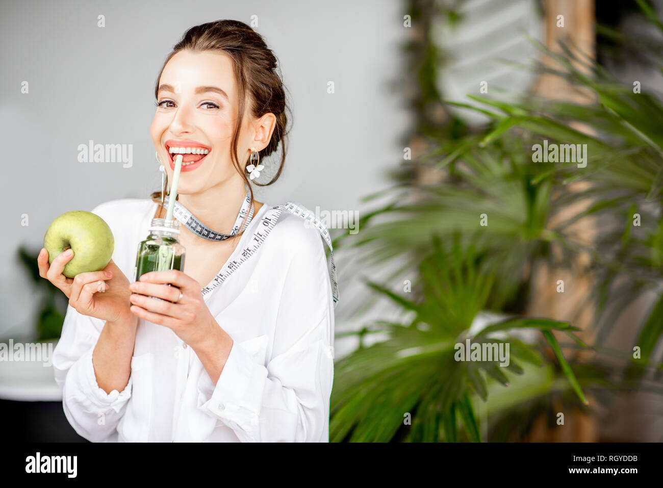Ritratto di una giovane donna con Apple e drink frullato in ambienti chiusi. Mangiare sano e wight il concetto di perdita Foto Stock