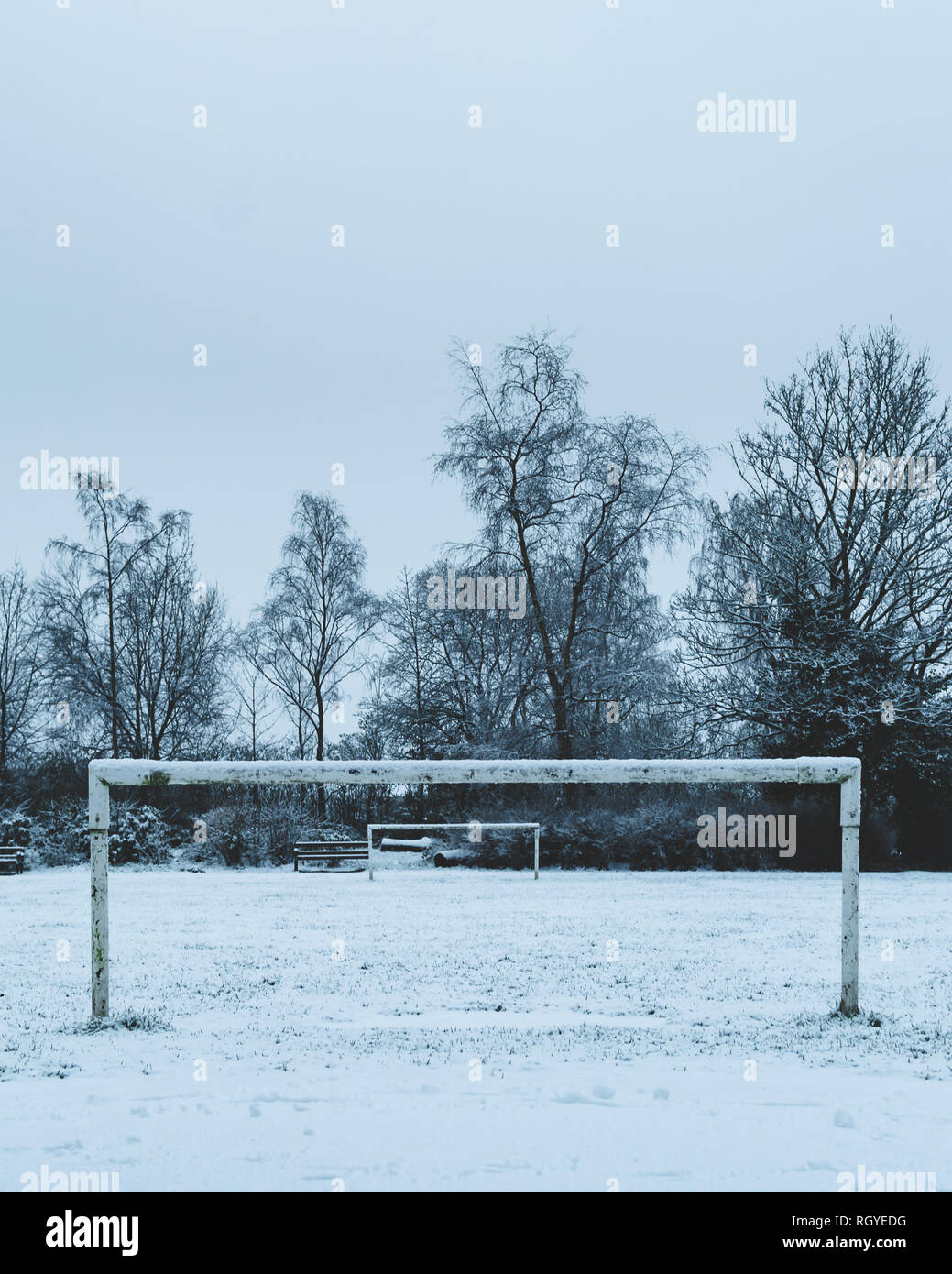 Un inverno di colpo di un piccolo campo da calcio attraverso i pali con il passo coperta da fitti bianco della neve Foto Stock