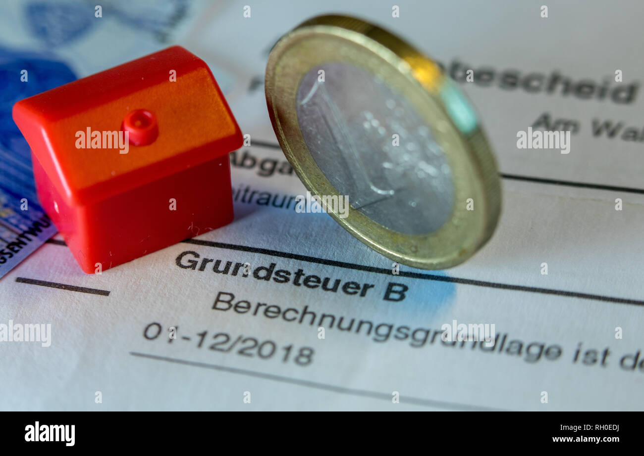 Schwerin, Germania. 30 gen, 2019. Illustrazione - un euro moneta di denaro come pure un giocattolo casa riposare su un'imposta avviso di accertamento per il pagamento della tassa di proprietà. Schleswig-Holstein ha introdotto una nuova proposta di compromesso nei difficili negoziati tra i governi federali e statali su una riforma dell'imposta immobiliare. Le discussioni sulla riforma delle tasse sulla proprietà continuerà in occasione della prossima riunione ministeriale del 01.02.2019. Credito: Jens Büttner/dpa-Zentralbild/ZB/dpa/Alamy Live News Foto Stock