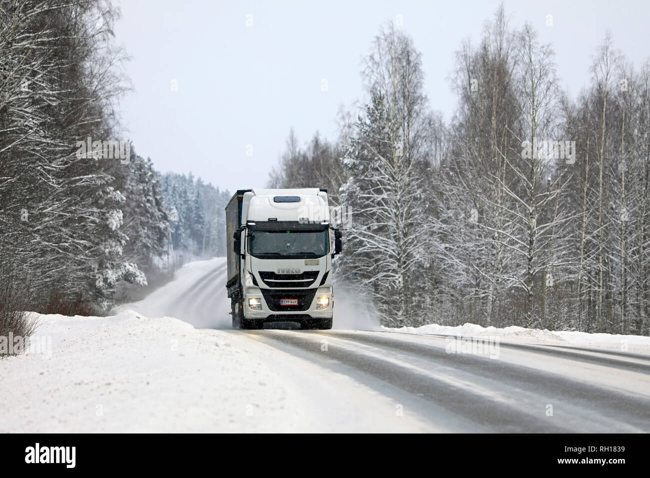 Salo, Finlandia - 27 Gennaio 2019: inverno paesaggio stradale con il bianco Iveco Stralis trasporto merci carrello in nevicata. Foto Stock