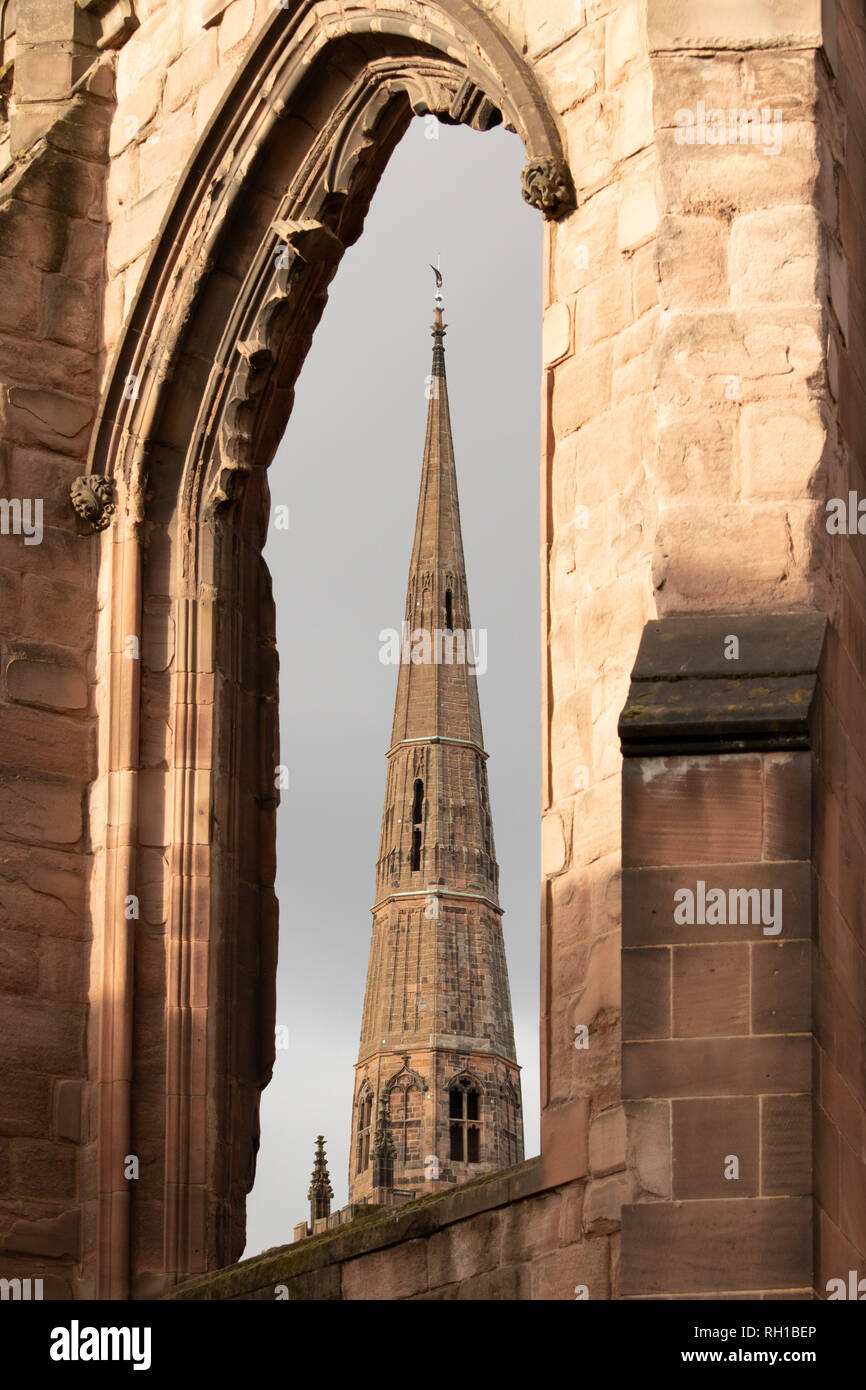 La guglia della chiesa della Santa Trinità visto attraverso le finestre di Coventry vecchia cattedrale Foto Stock