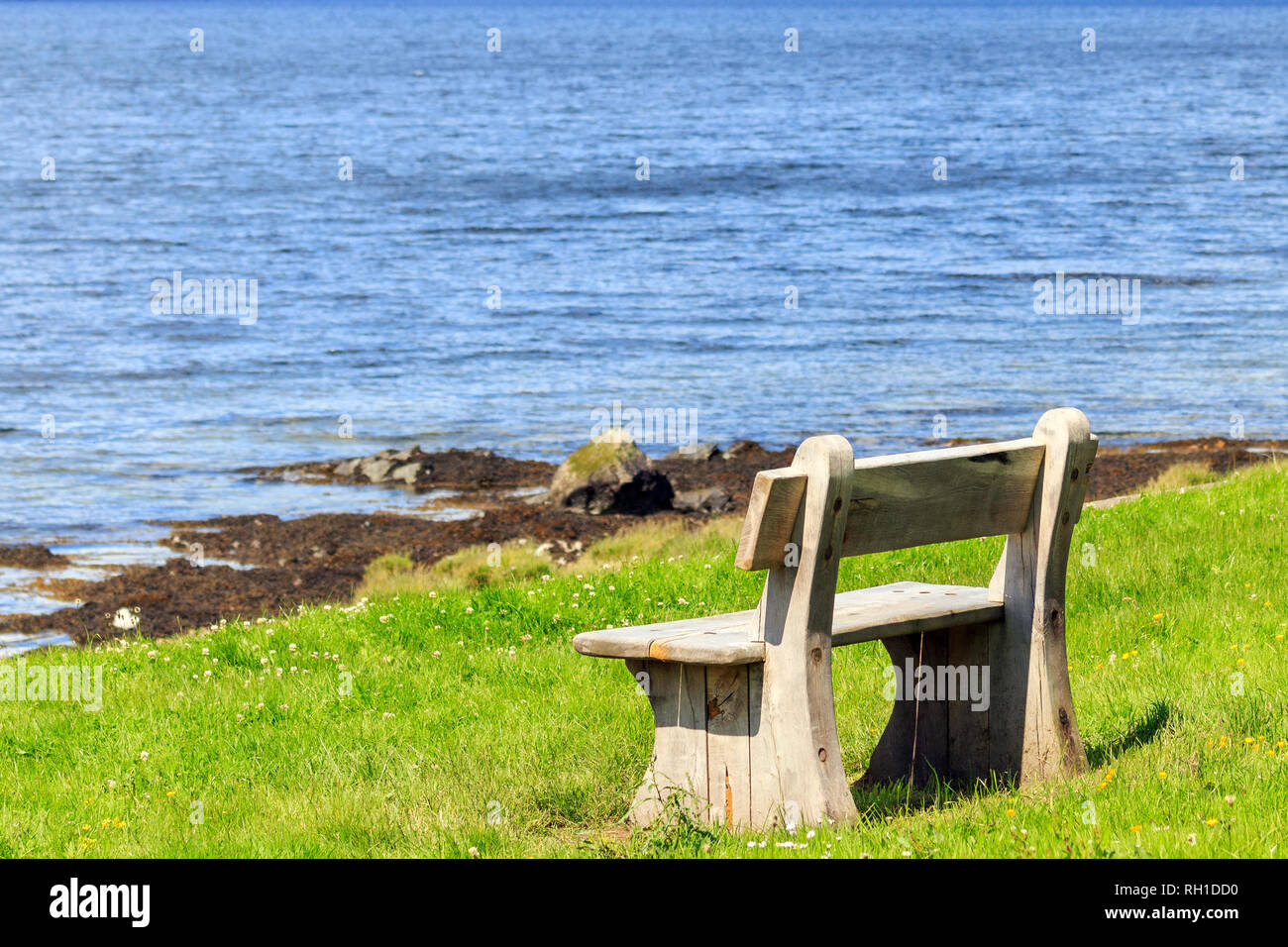 Soleggiato panca in legno sede guardando fuori al bordo delle acque della Scottish Loch Foto Stock
