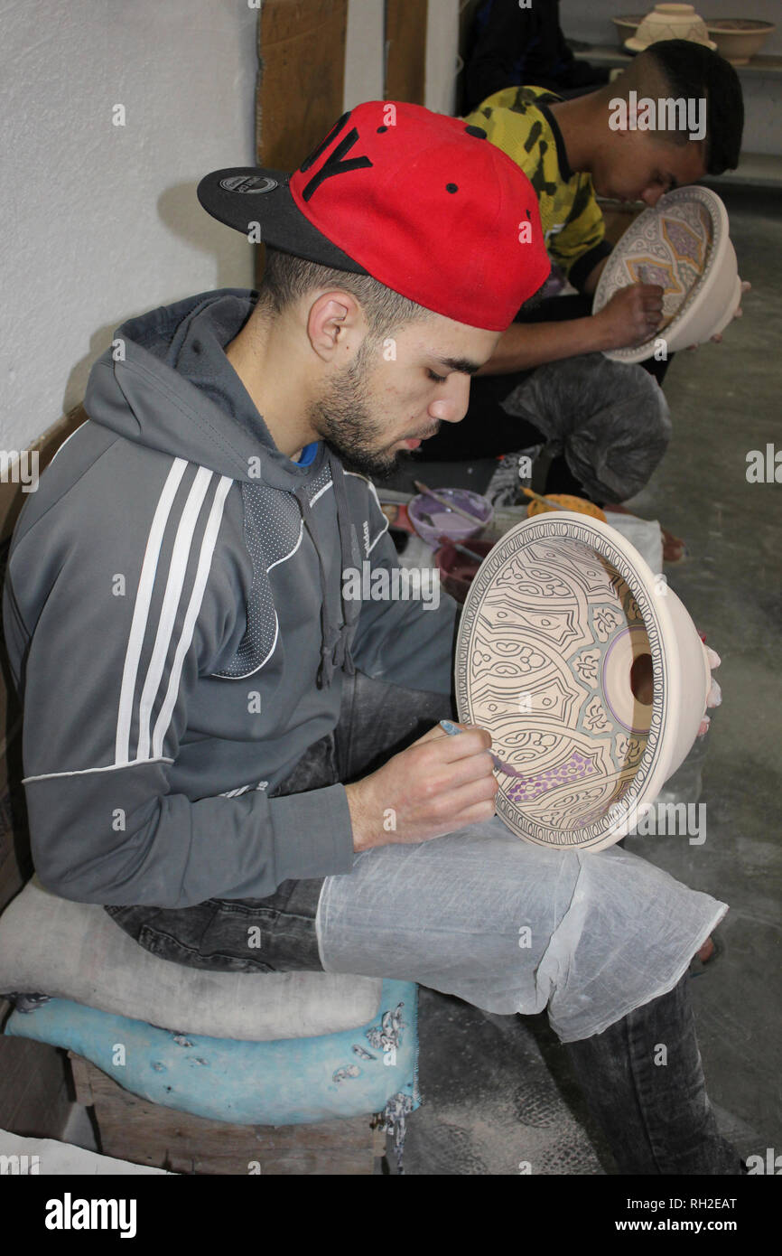 Giovani uomini pittura ciotole di ceramica in un ceramiche co-operativa in Fez, in Marocco Foto Stock