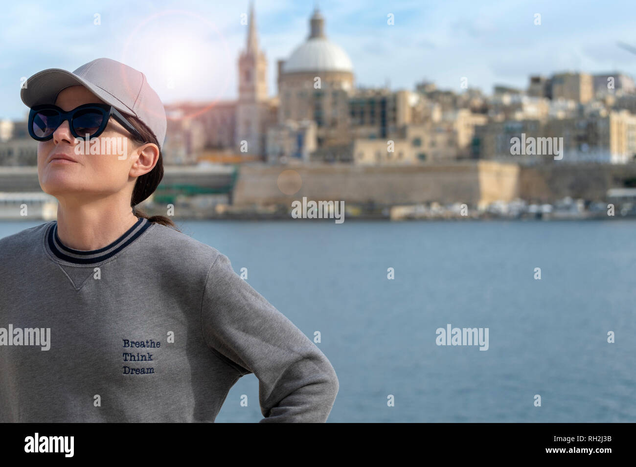 In prossimità di una rilassata donna che indossa una felpa con lo slogan "respirare, pensare, sogno". La Valletta, Malta sfondo. Foto Stock