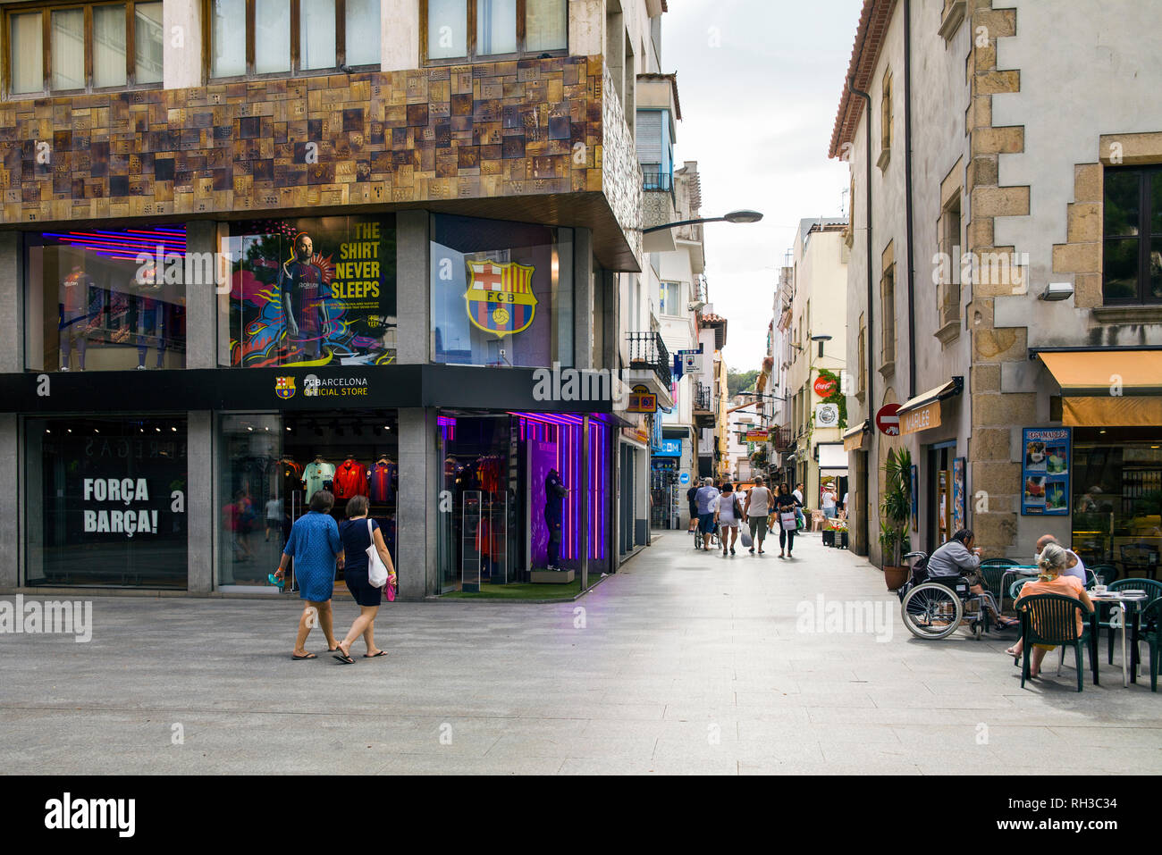 Negozi e caffetterie vicino le strette strade di Lloret de Mar, nel centro cittadino di Lloret, Spagna. I turisti camminando per le strade della città. Foto Stock