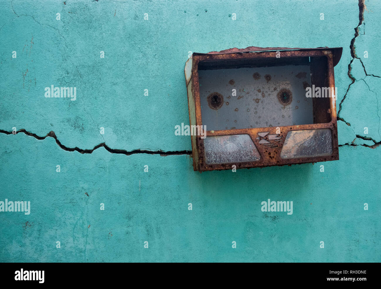 Teal parete testurizzata, con traslazione lungo il crack e un metallo arrugginito mailbox Foto Stock