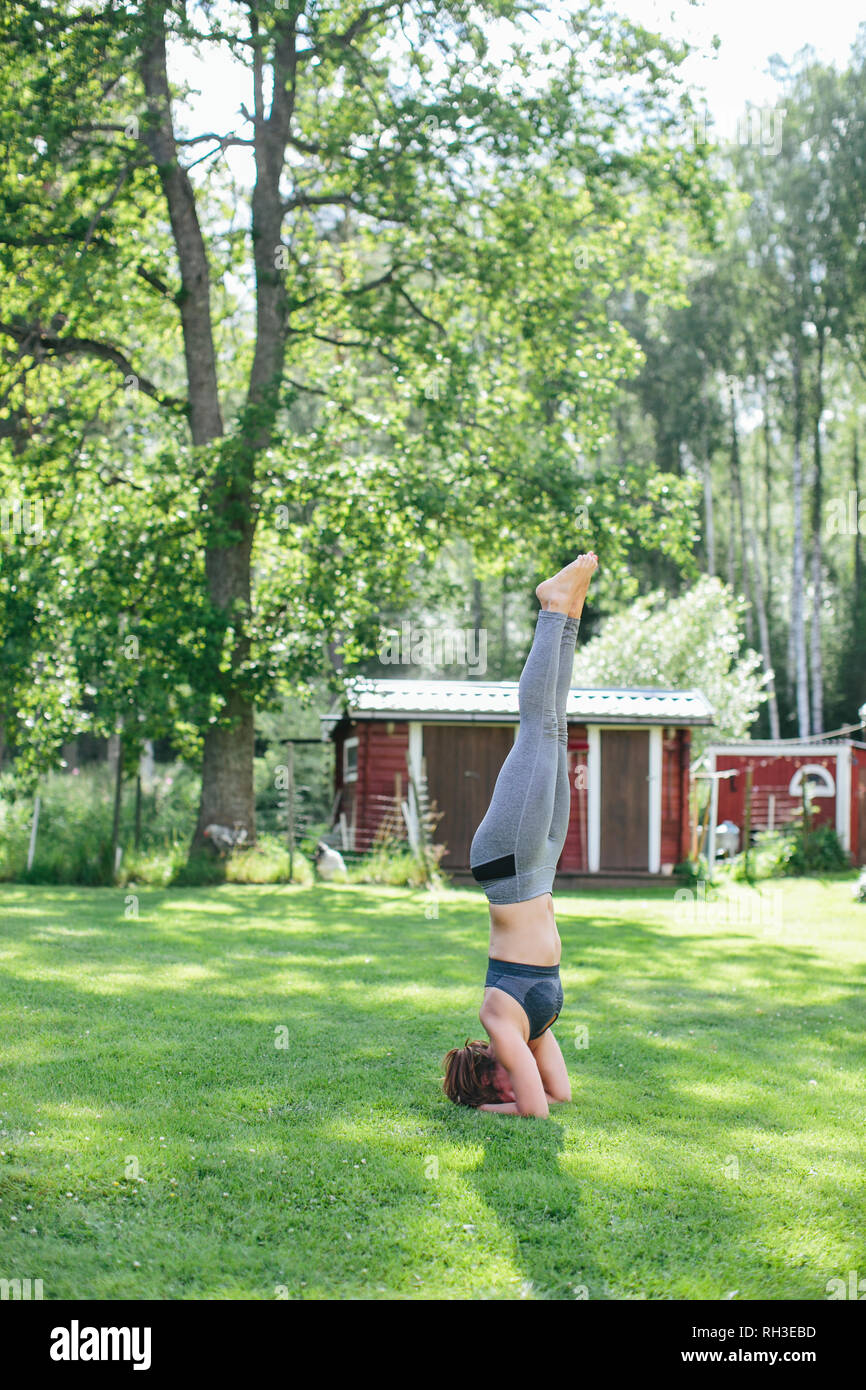 Donna facendo headstand Foto Stock