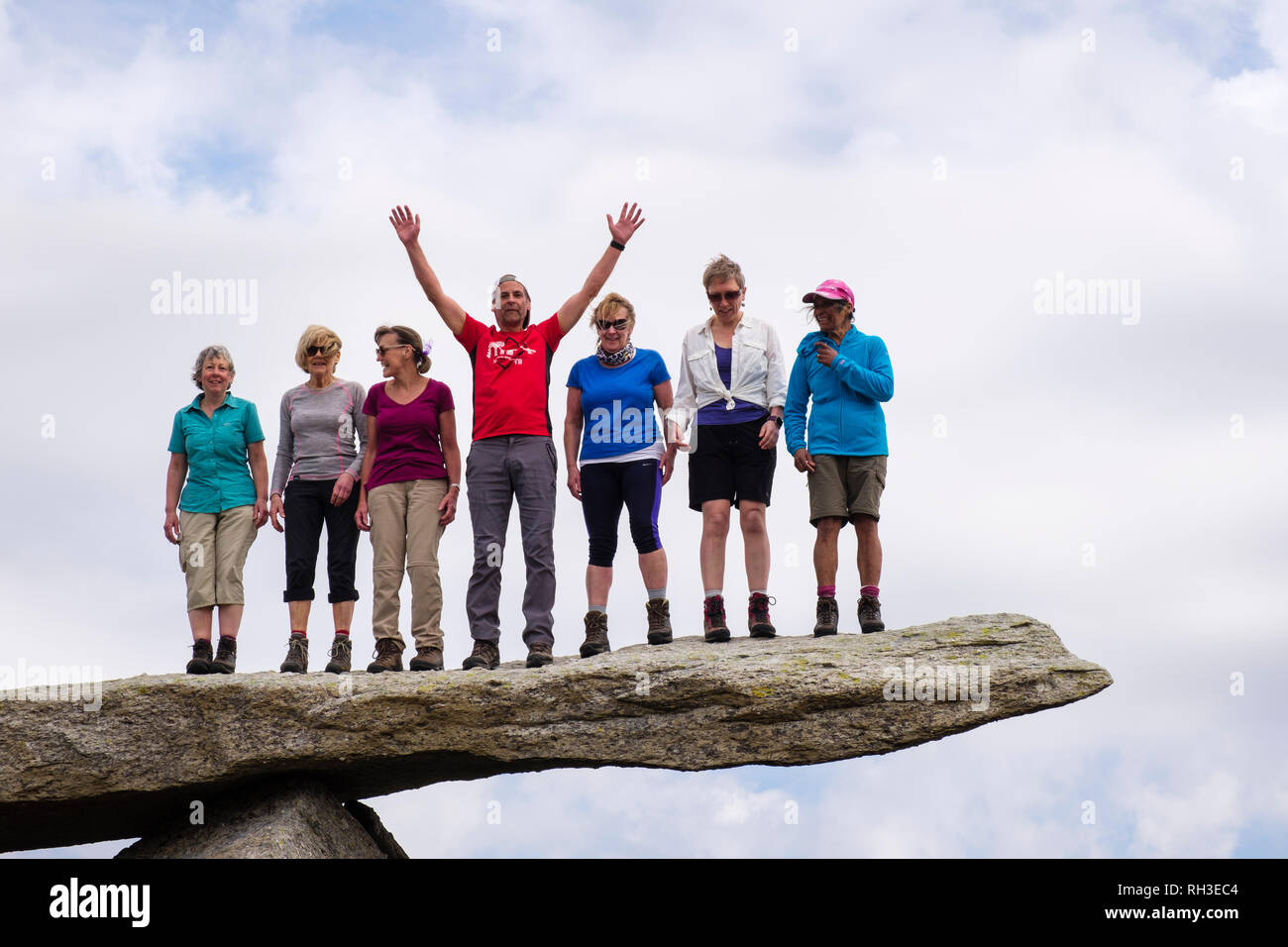 Un gruppo di escursionisti felici alcune persone che si trovano sulla roccia a sbalzo sulla montagna Glyder Fach nel Parco Nazionale di Snowdonia. Ogwen Conwy Galles Regno Unito Gran Bretagna Foto Stock