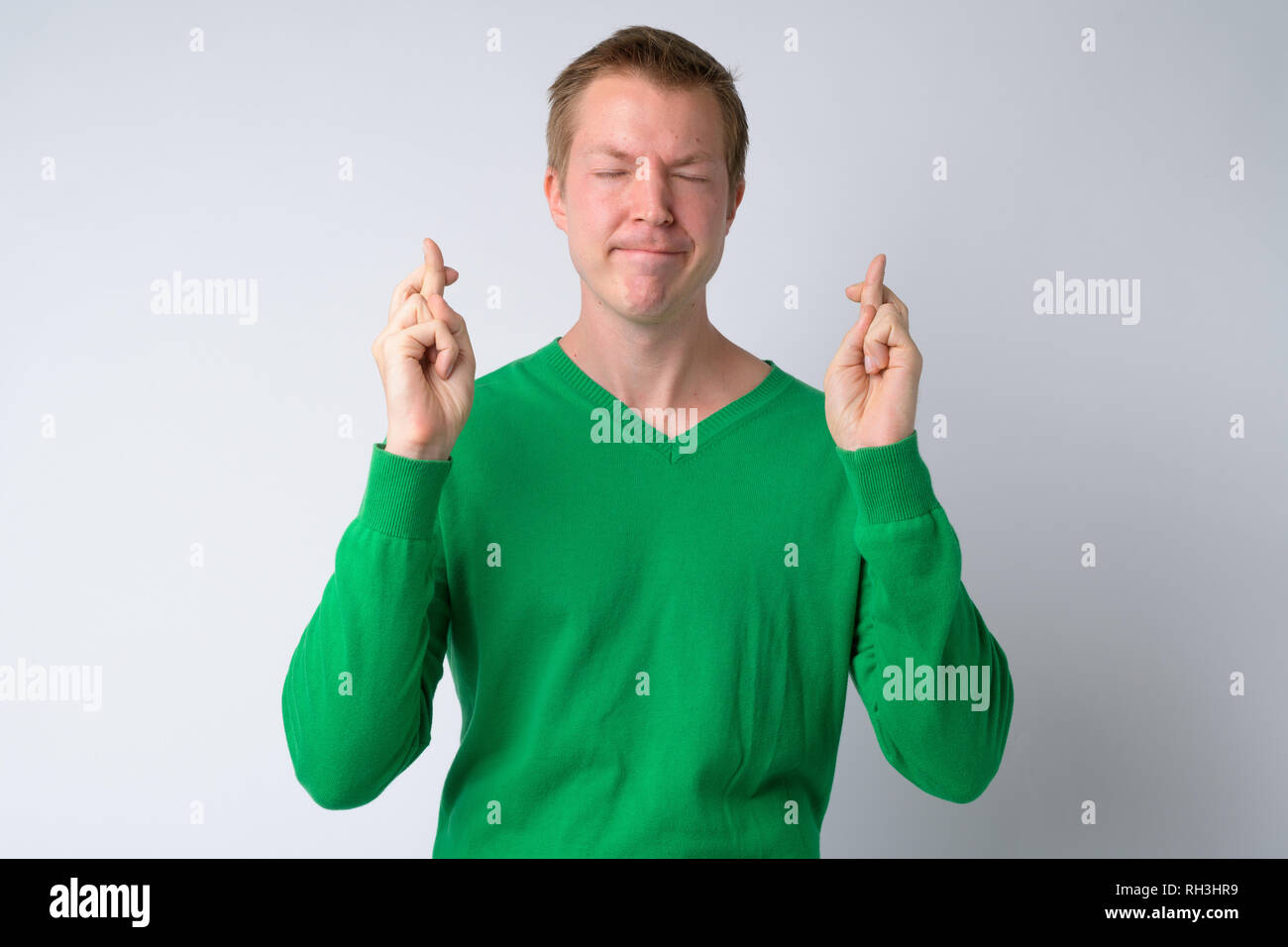Ritratto di giovane uomo bello che desideri con le dita incrociate Foto Stock