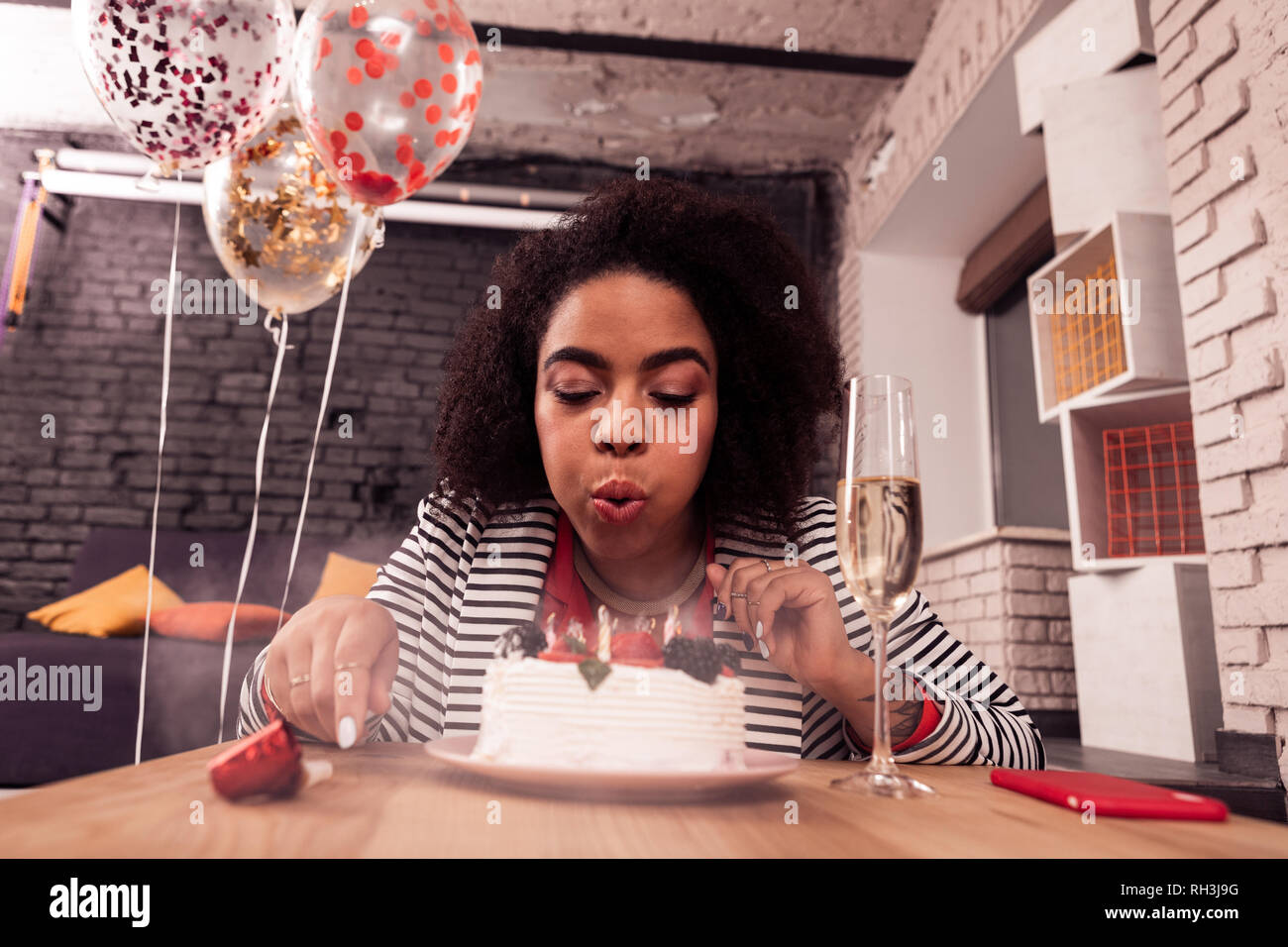 Piacevole afro american donna soffiando a candele Foto Stock