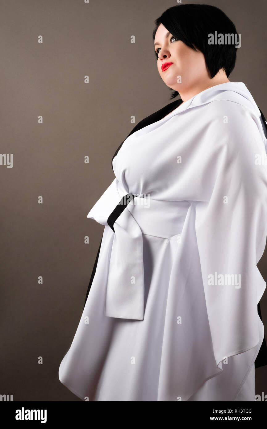 Grasso donna in abiti alla moda isolato su sfondo grigio Foto Stock