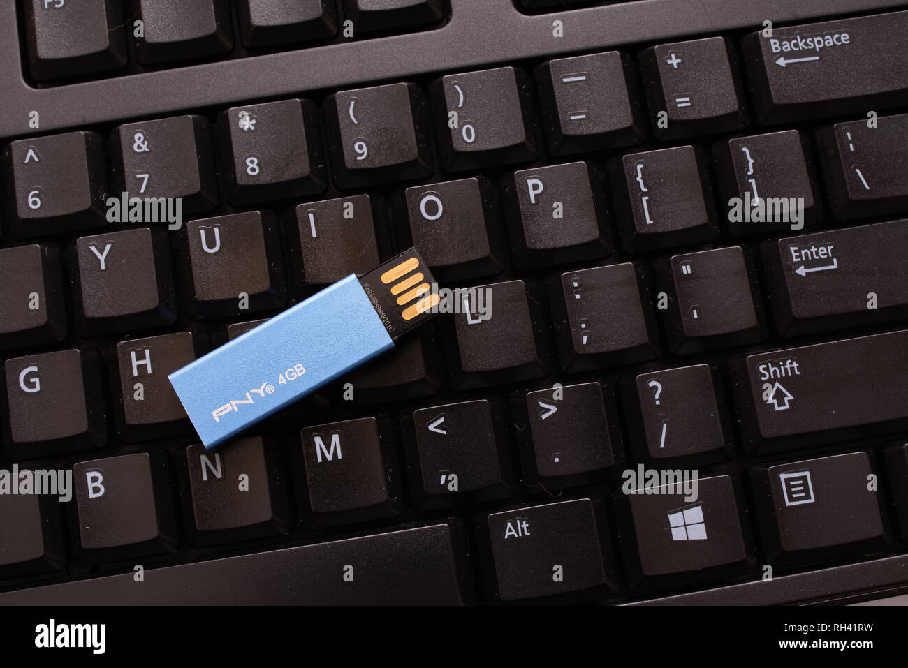 Un nero della tastiera del computer con un colore blu pallido miniatura PNY memory stick per la memorizzazione di dati o memoria aggiuntiva. Foto Stock