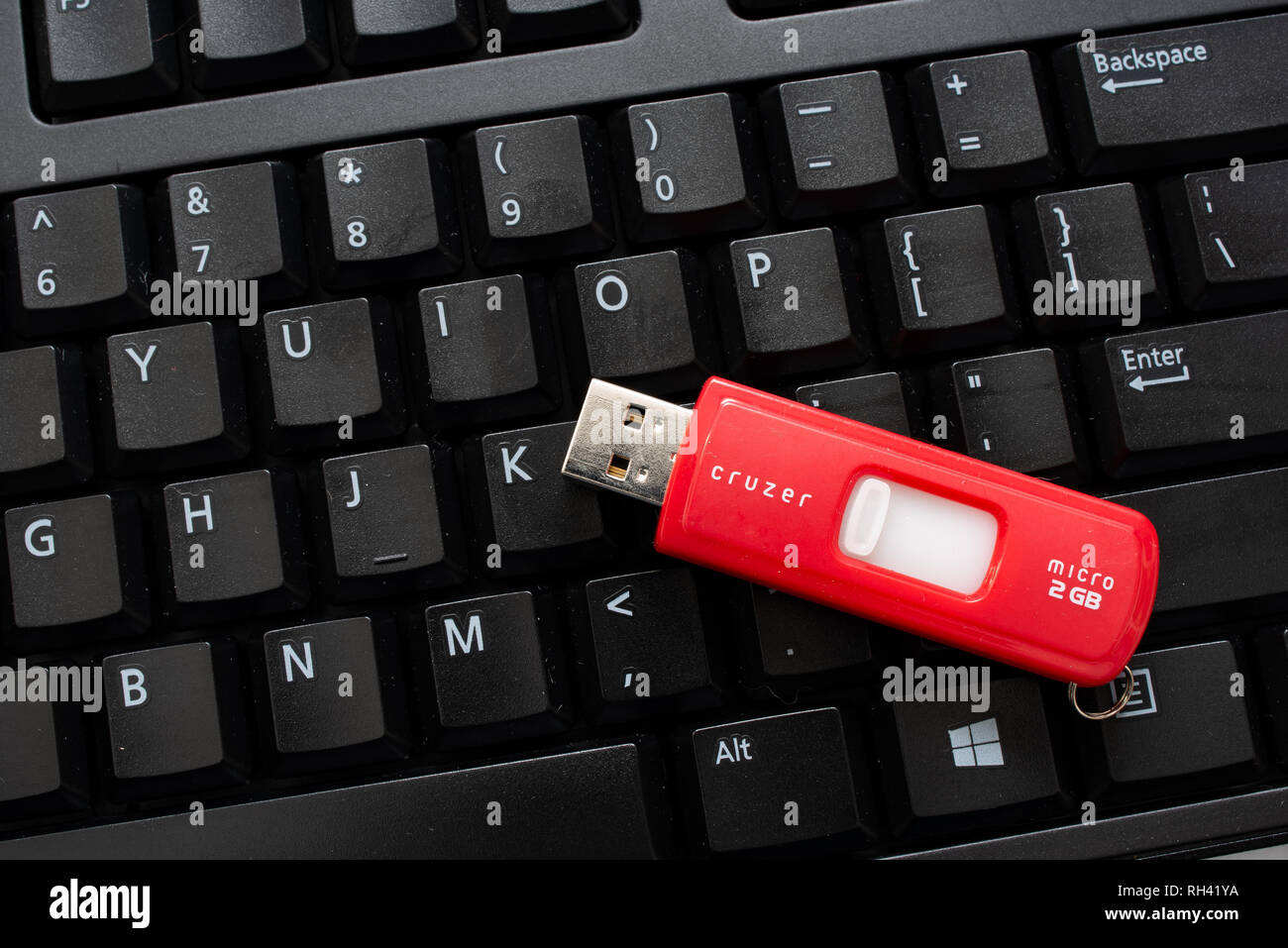 Un nero della tastiera del computer con un rosso cruzer memory stick per la memorizzazione di dati o memoria aggiuntiva. Foto Stock
