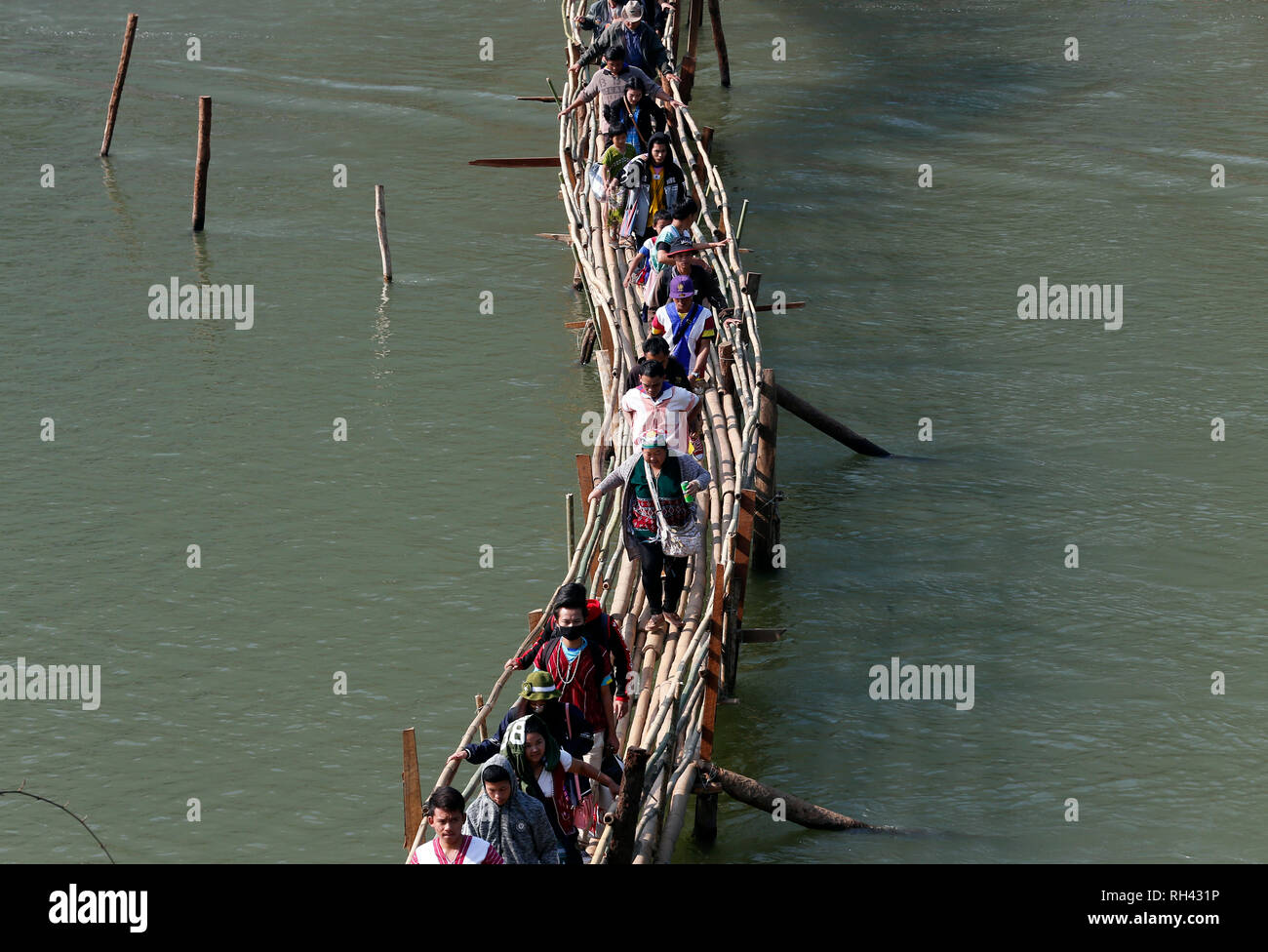 I rifugiati Karen veduto camminare su un ponte di bambù come loro attraversare un fiume torna alla Thailandia dopo la cerimonia. Il settantesimo anniversario della Rivoluzione Karen giorno alla Baia di Thay Hla in stato di Karen lungo il confine Thai-Myanmar. Foto Stock