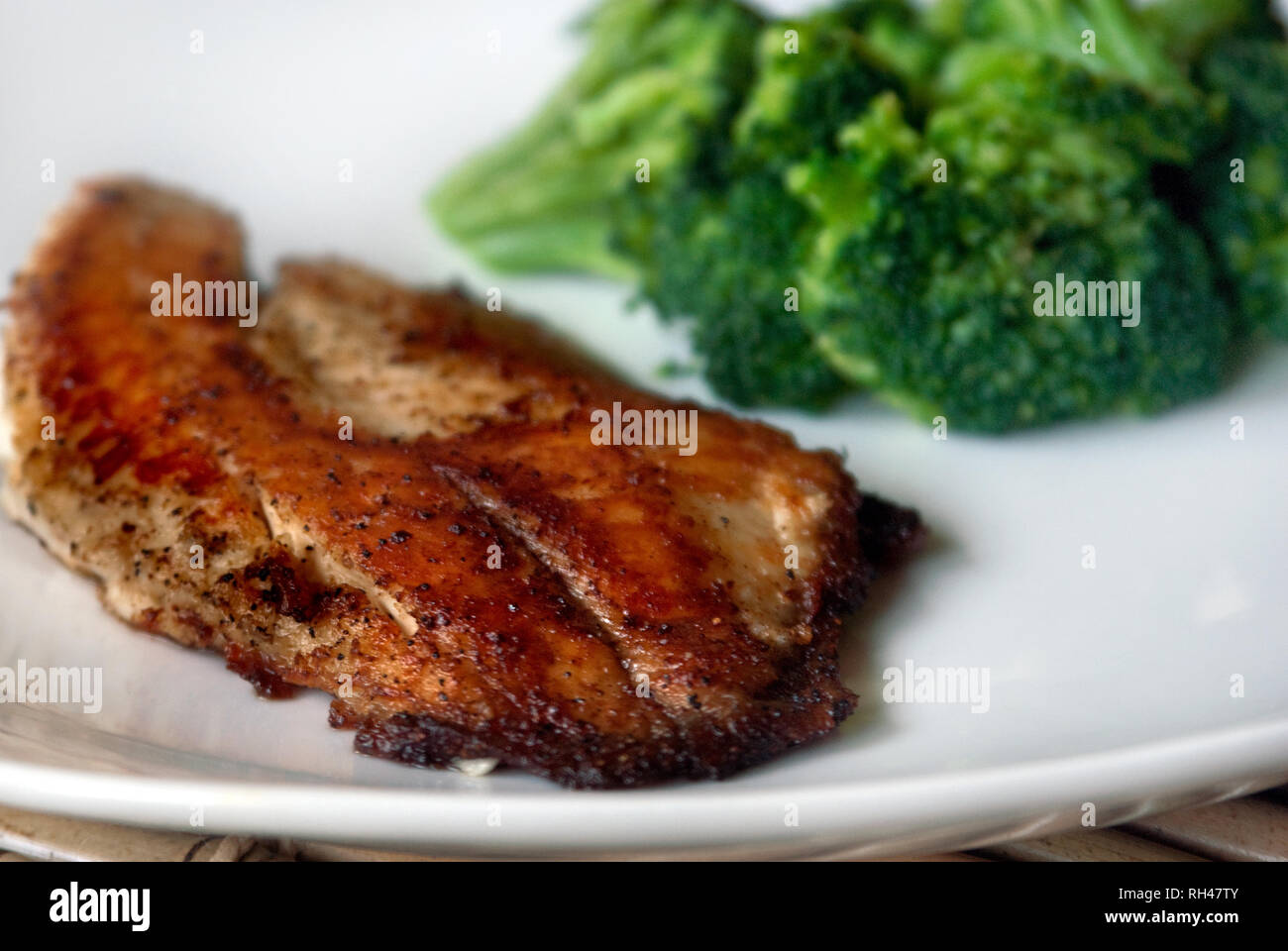 Scottato in padella tilapia è servita con un lato di broccoli cotti al vapore. Foto Stock