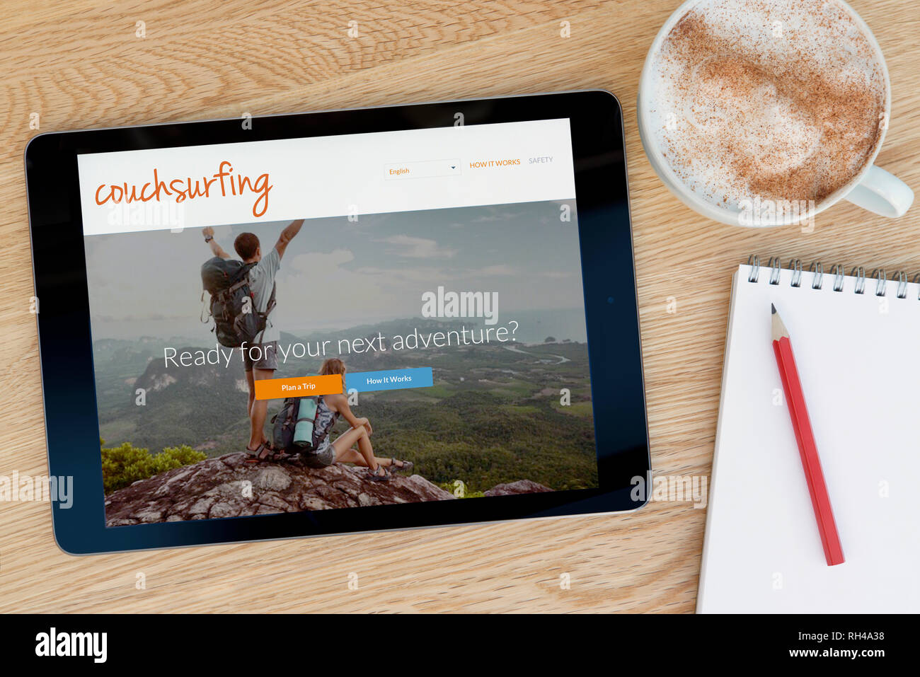 Il Couchsurfing funzionalità del sito su un iPad dispositivo tablet pc che si appoggia su una tavola di legno accanto a un blocco note (solo uso editoriale). Foto Stock