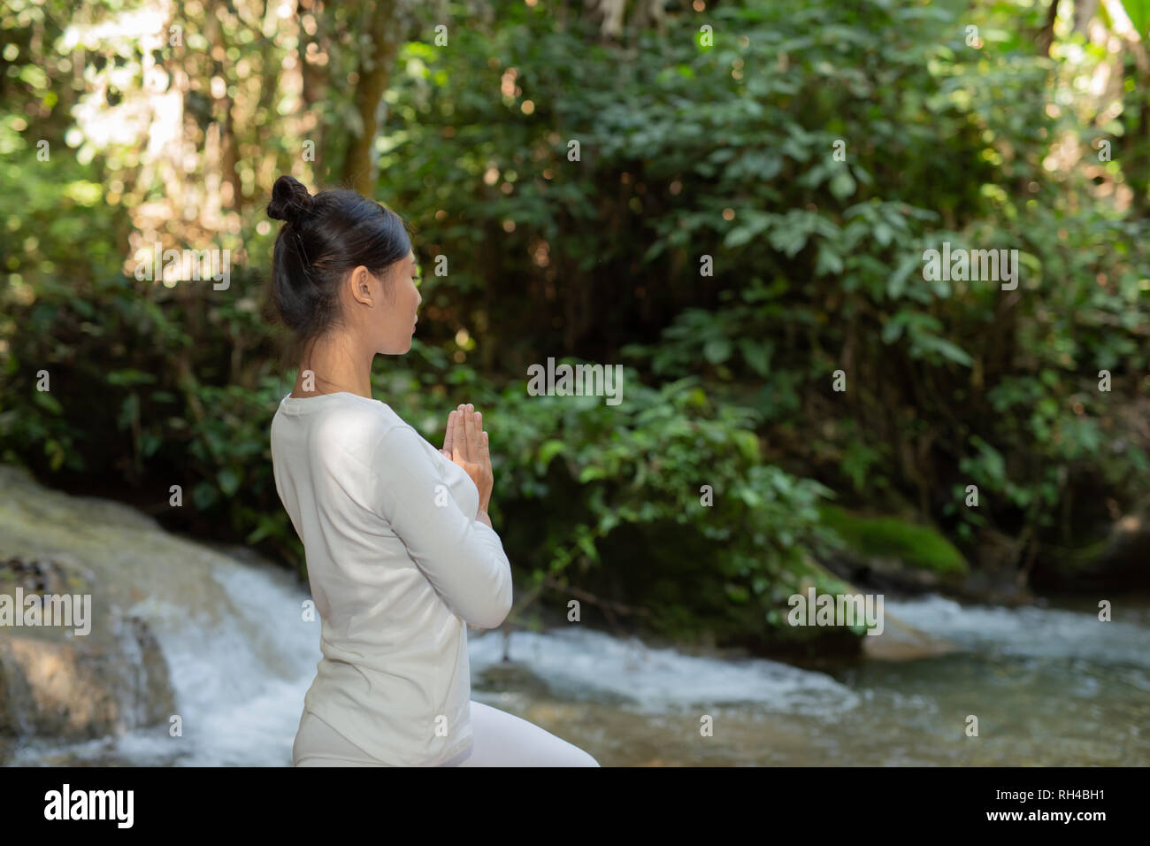 Belle ragazze stanno giocando lo yoga al parco. Tra le cascate naturali della foresta, i concetti di esercizio Foto Stock