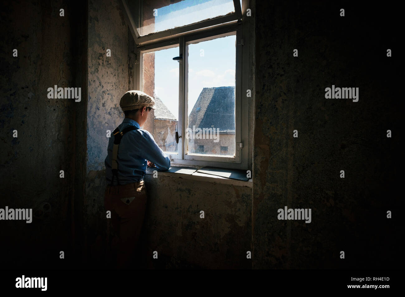 Ragazzo guardando fuori finestra soleggiata Foto Stock