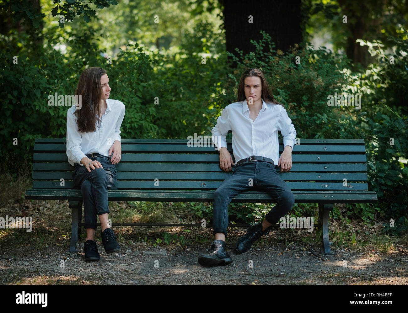 Immagini multiple uomo seduto su una panchina nel parco con le gambe incrociate e gambe divaricate Foto Stock