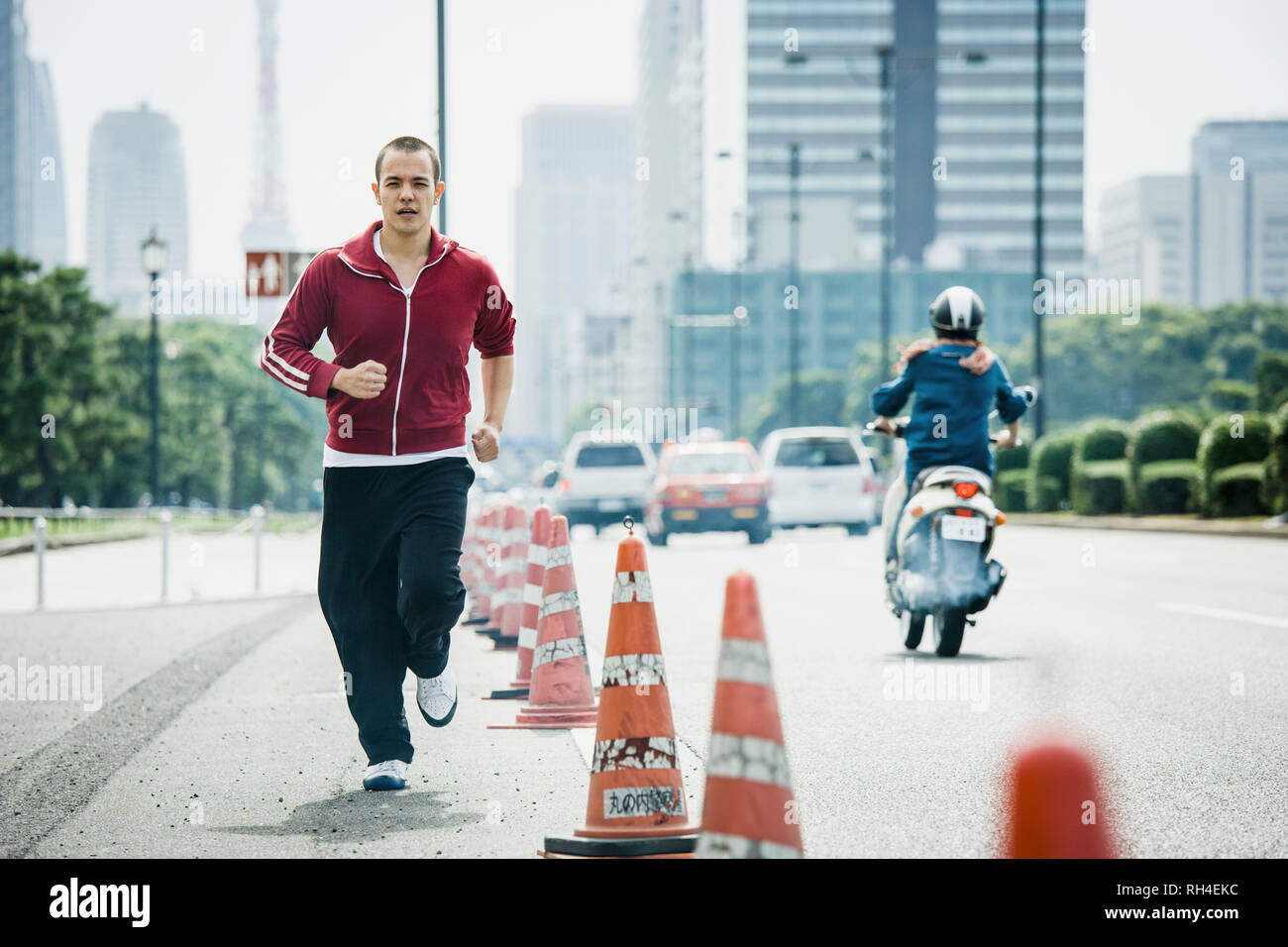 Giovane uomo jogging sulla strada urbana, Tokyo, Giappone Foto Stock