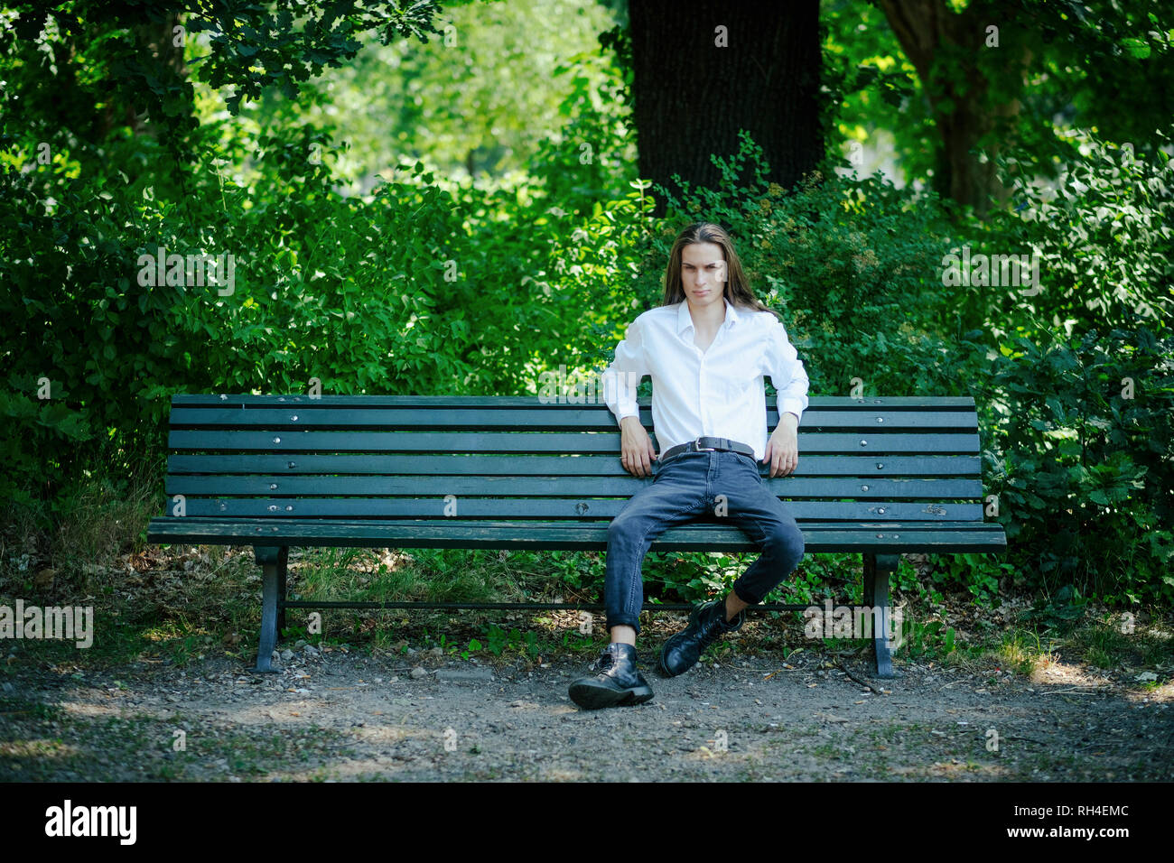 Ritratto fiducioso giovane uomo seduto su una panchina nel parco Foto Stock